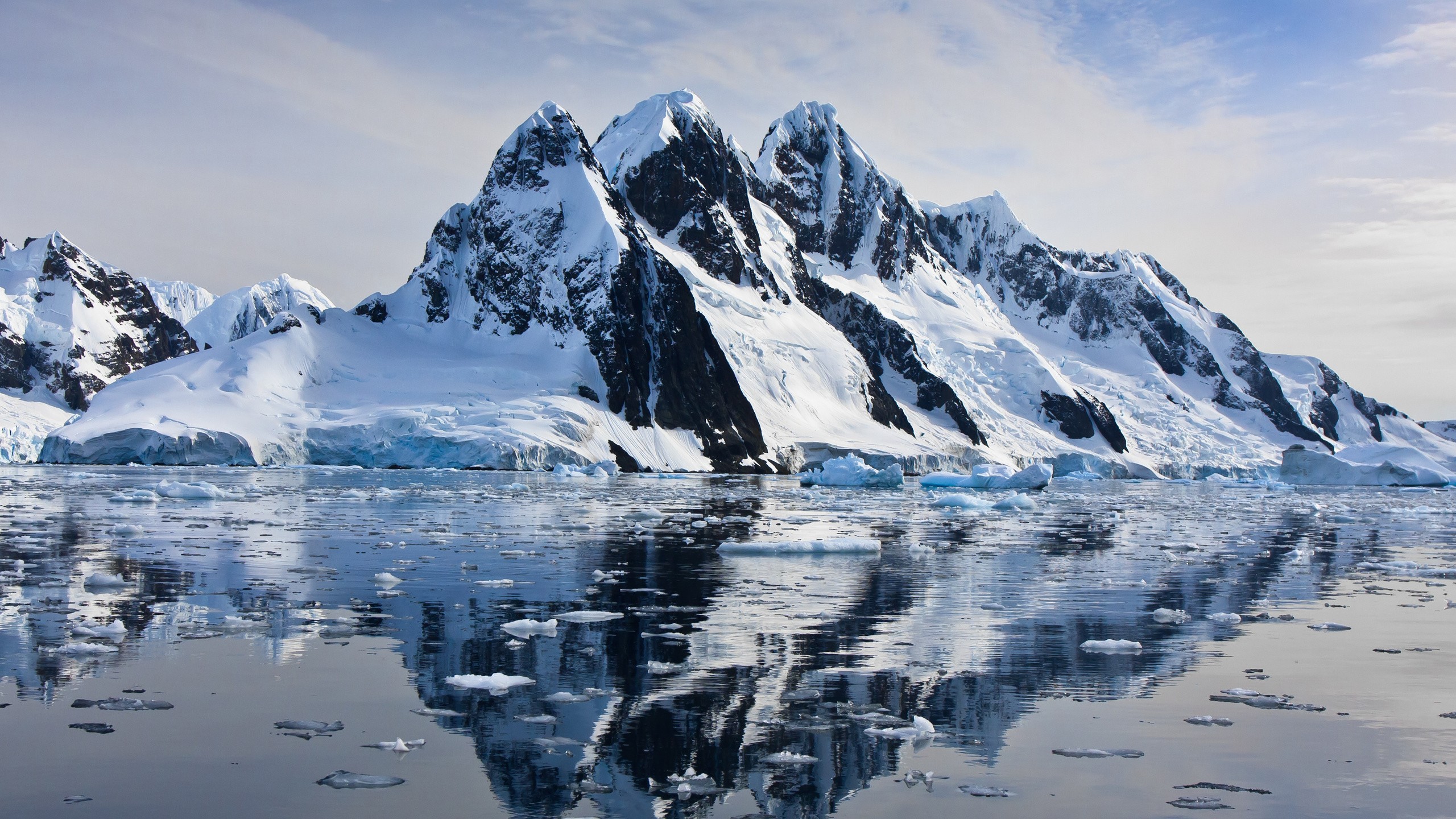 Snow-capped mountains reflected in the sea with ice floes HD Wallpaper
