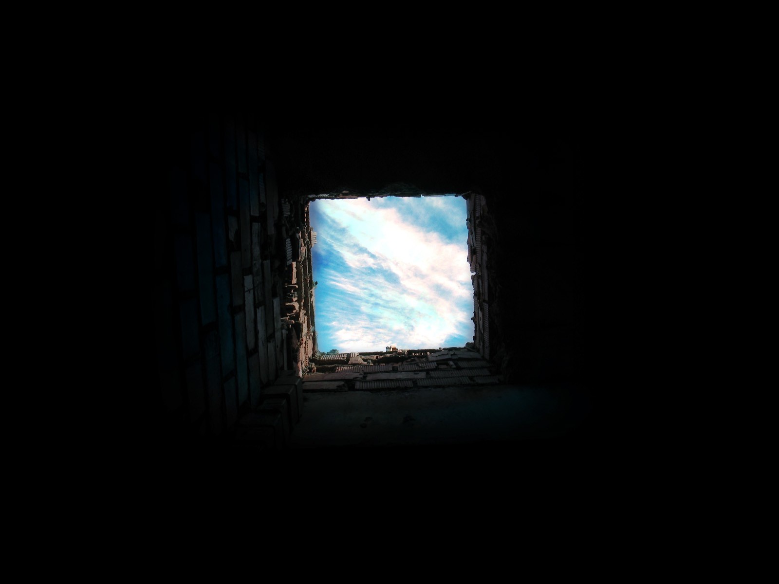 Worm's eye view of clouds through a brick opening HD Wallpaper