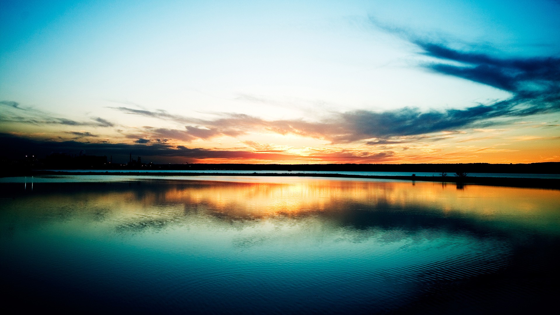 Sunset over a calm body of water with reflections HD Wallpaper