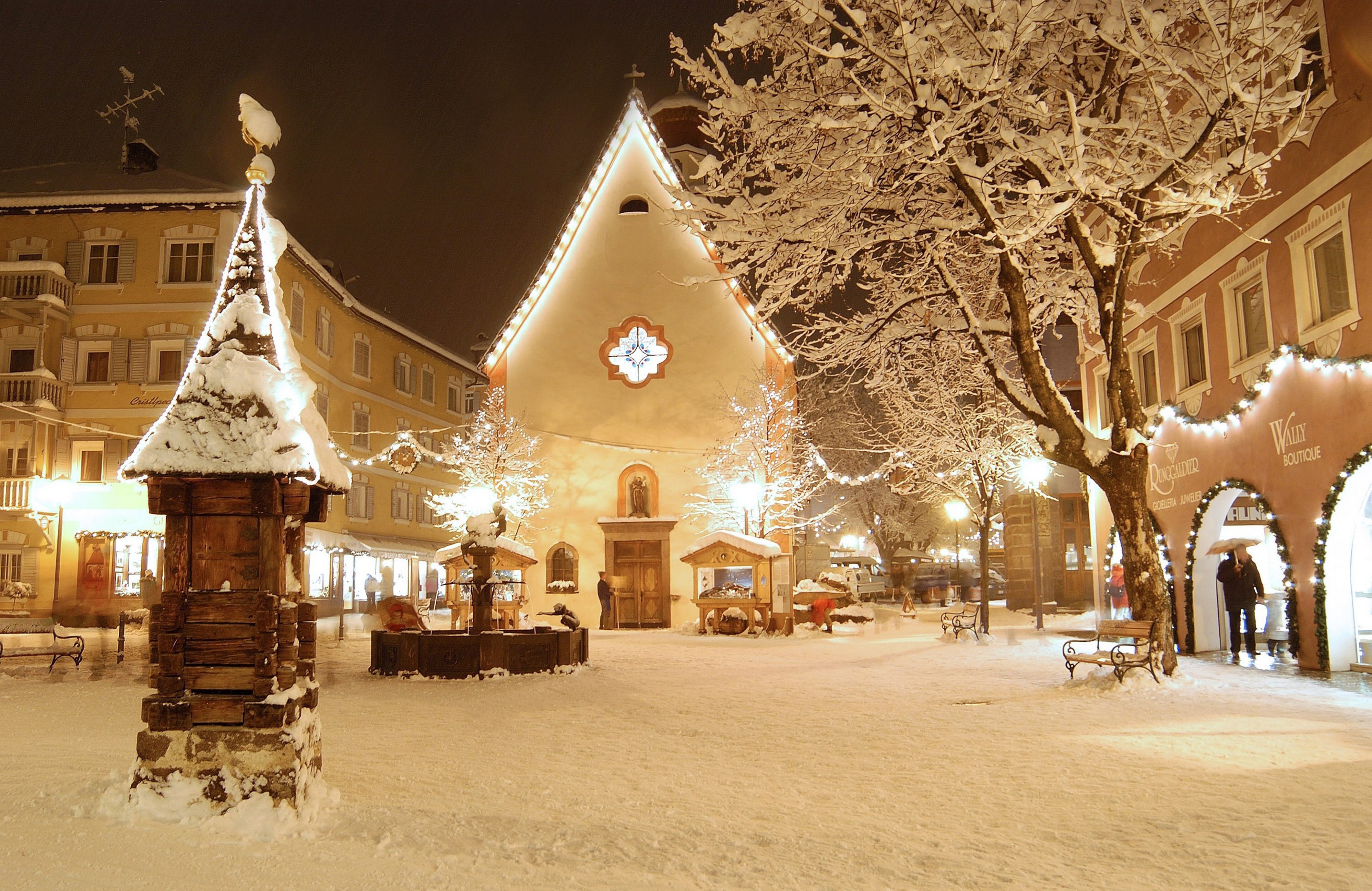 Snowy Christmas town square with church and fountain HD Wallpaper