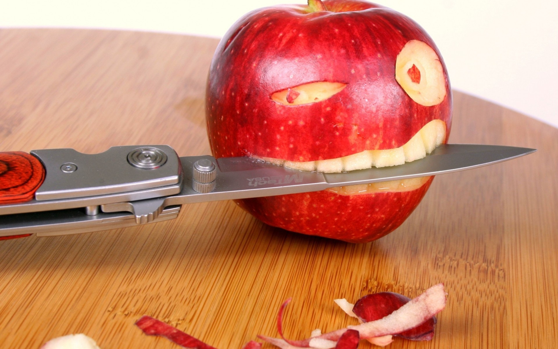 Apple carved into a face with a knife HD Wallpaper