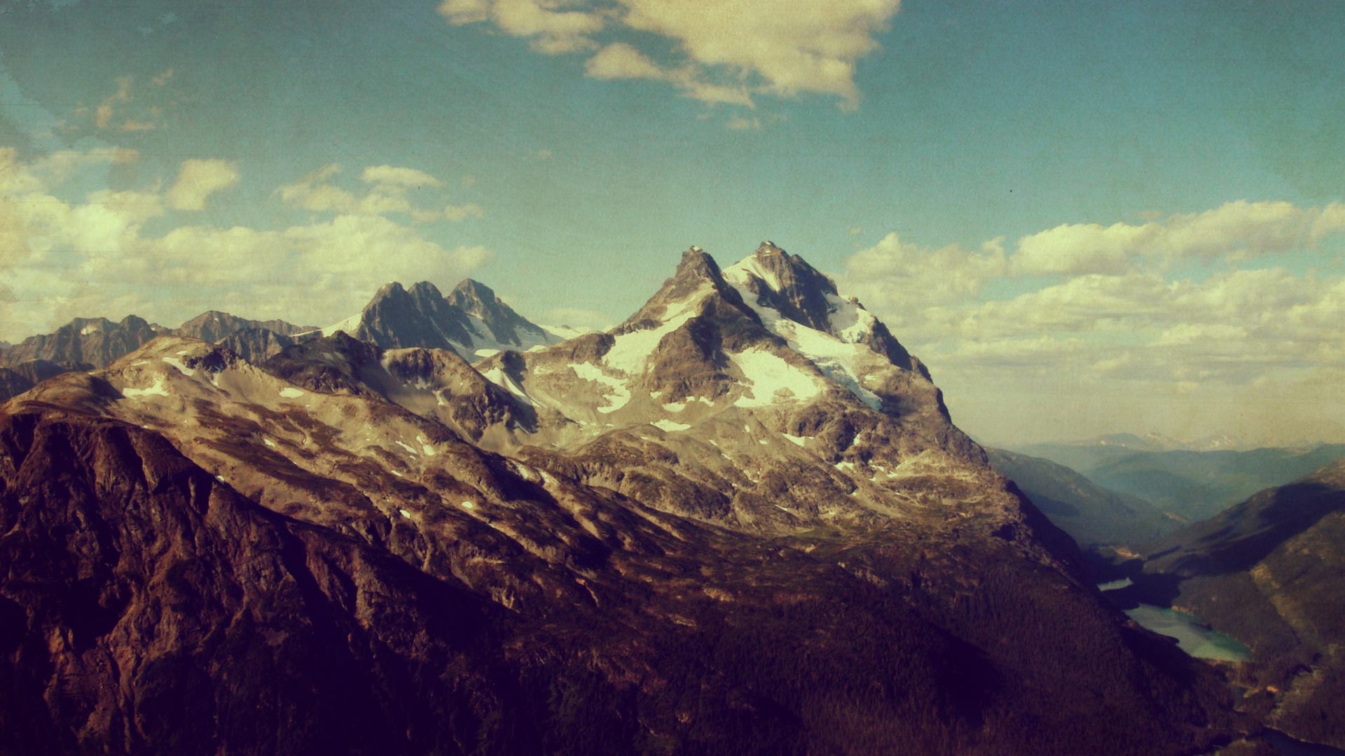 Snow-capped mountains under a cloudy sky HD Wallpaper