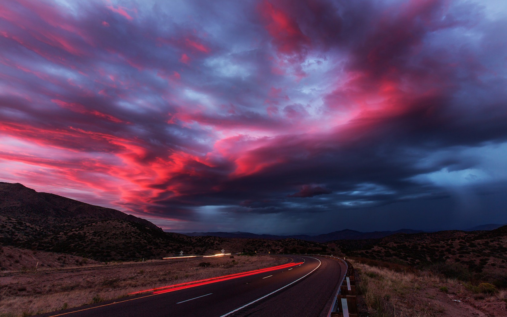 Road with dramatic sunset clouds and light trails HD Wallpaper