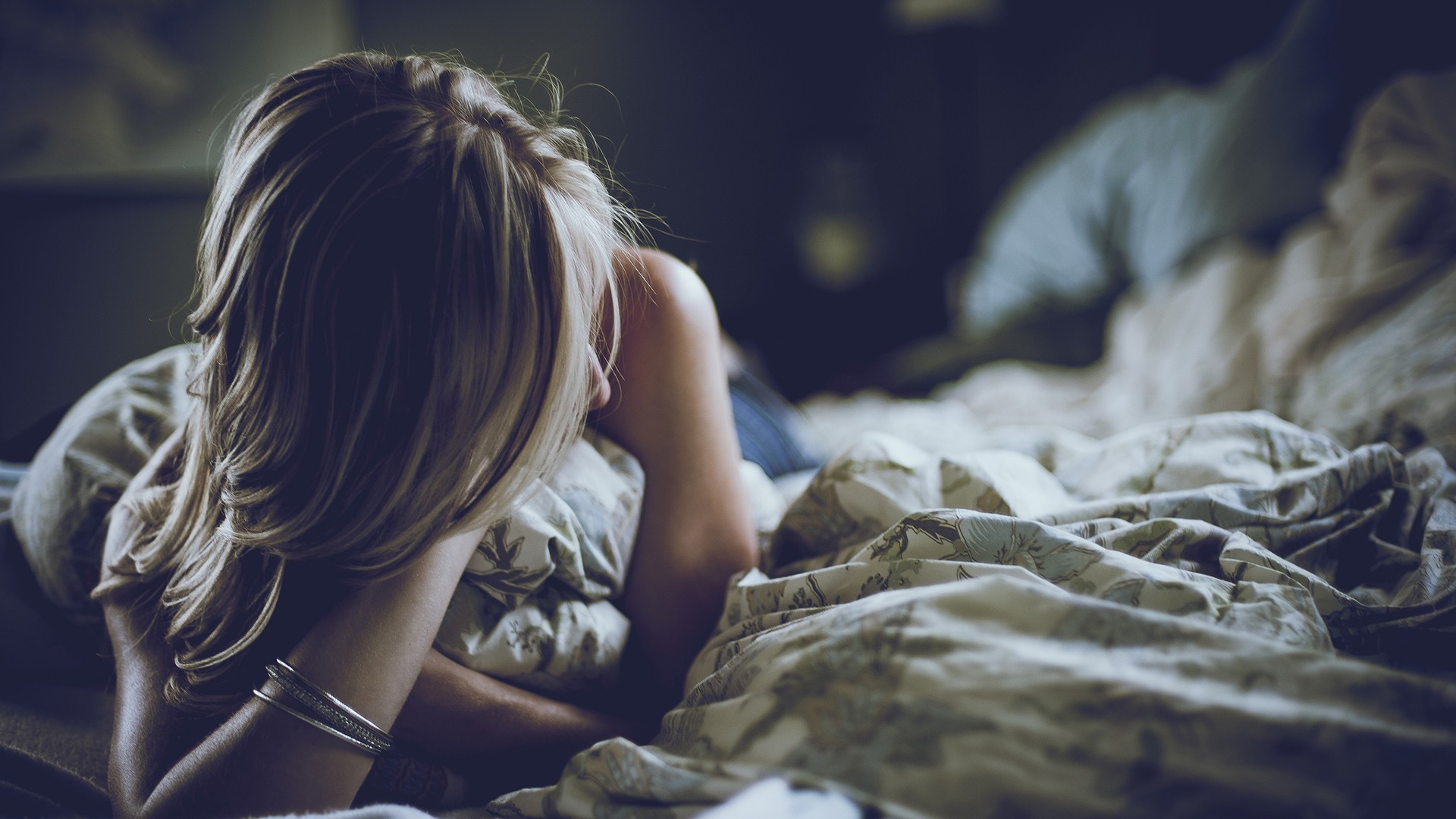 Woman with blonde hair lying in bed HD Wallpaper