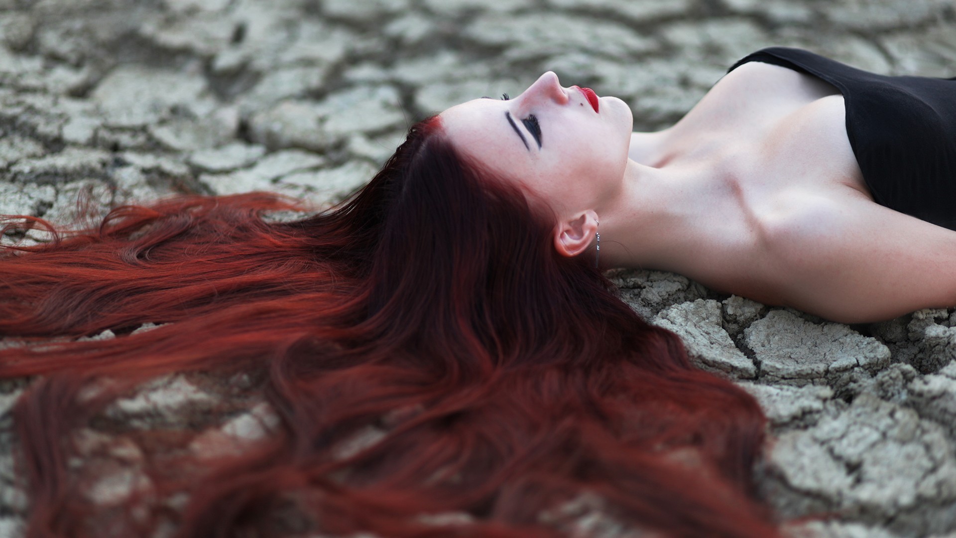 Redhead woman with long hair lying on cracked ground HD Wallpaper
