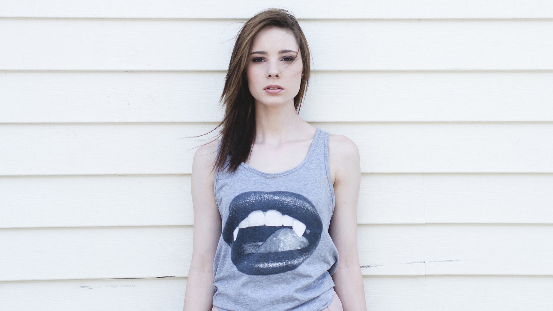 Woman in tank top with lips graphic standing against wall HD Wallpaper