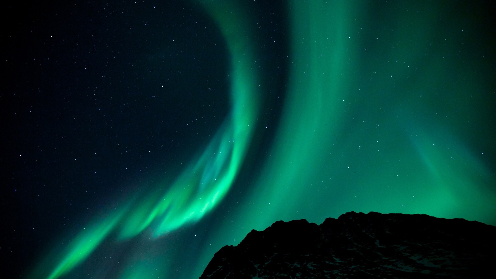 Aurora Borealis over a dark mountain landscape HD Wallpaper