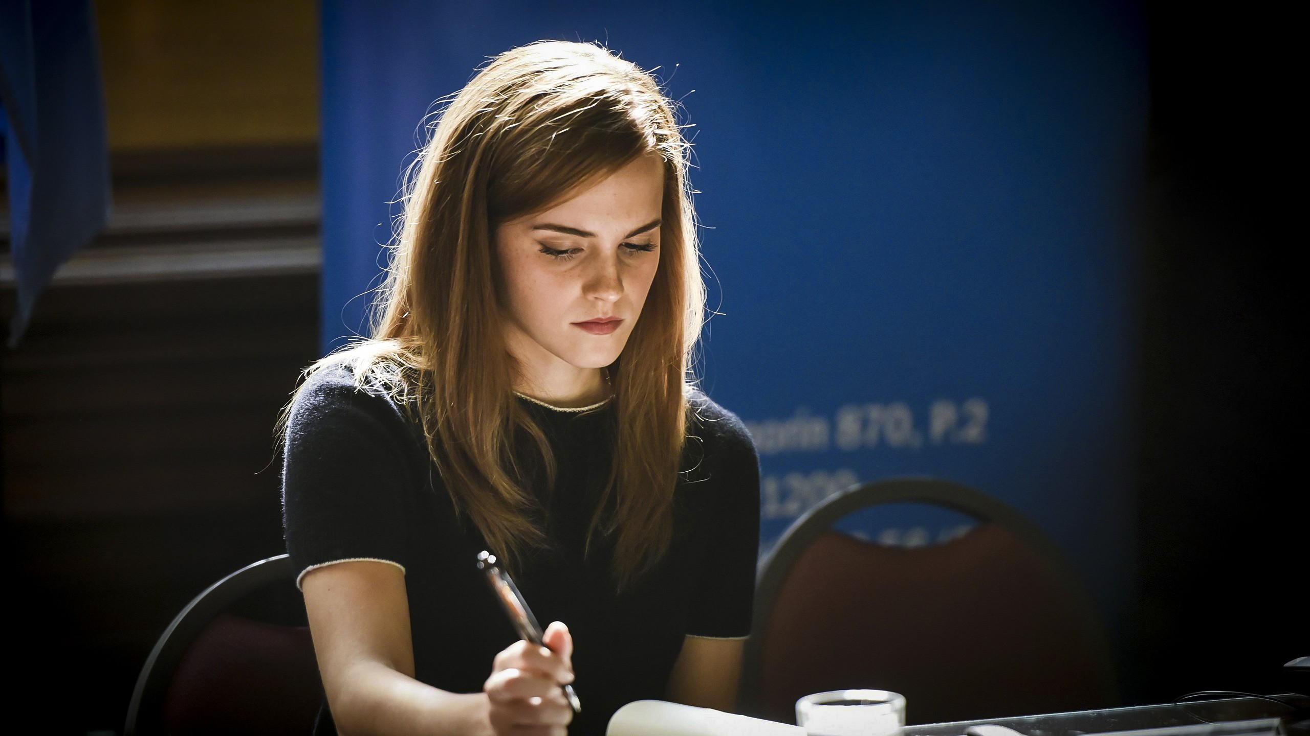 Emma Watson writing at a table HD Wallpaper