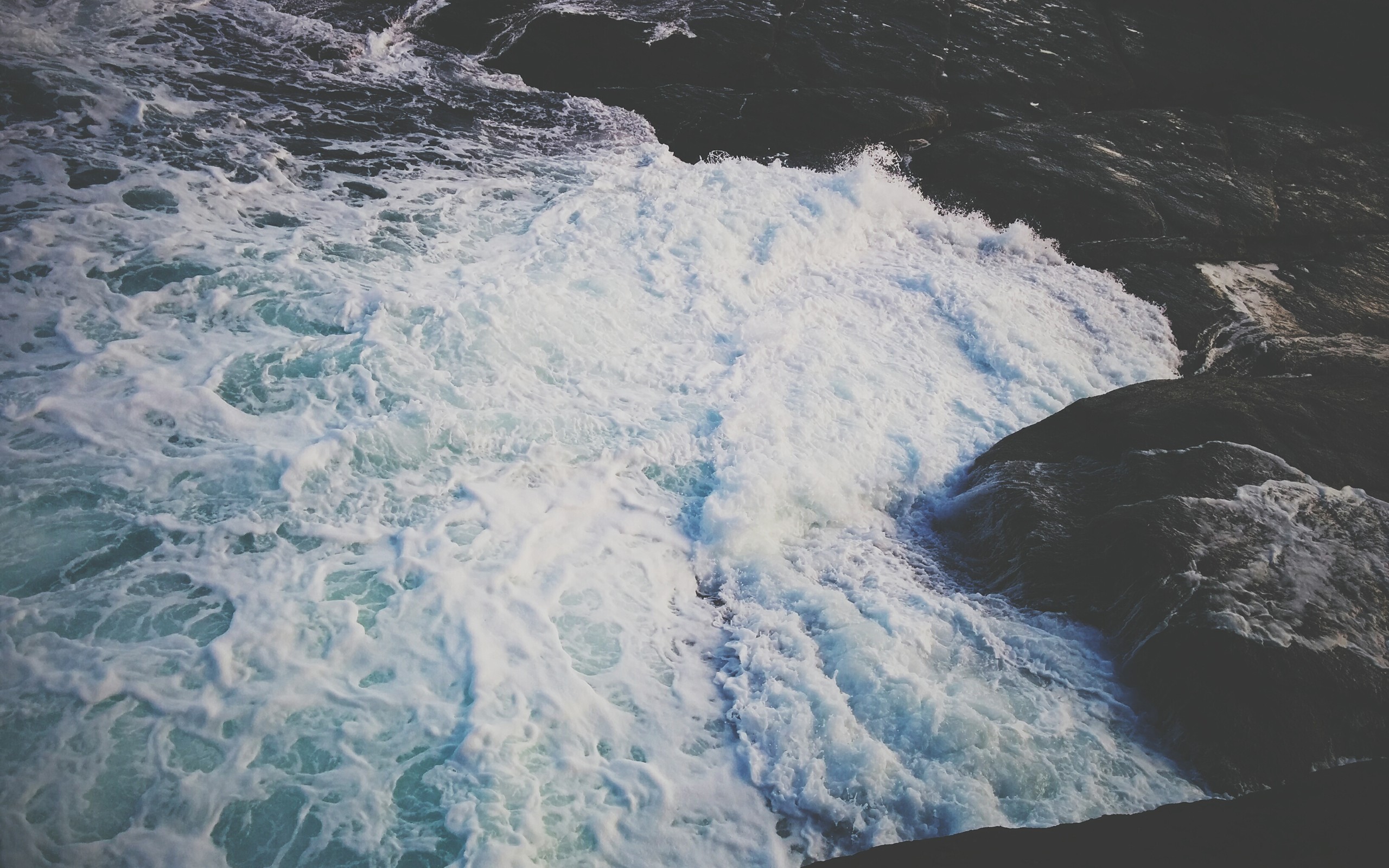 Waves crashing against dark rocks on the coast HD Wallpaper