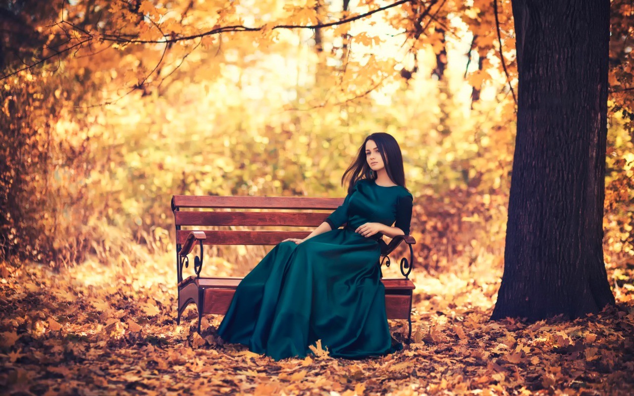 Woman in a green dress sitting on a bench in autumn HD Wallpaper