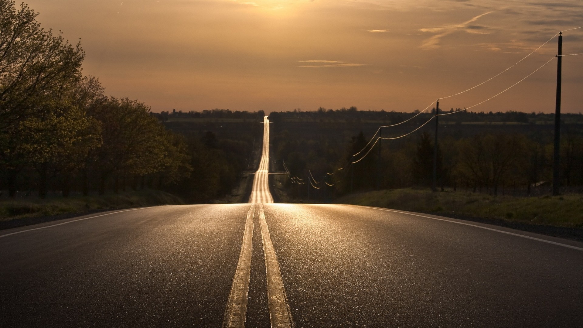 Long empty road stretching to the horizon at sunset HD Wallpaper