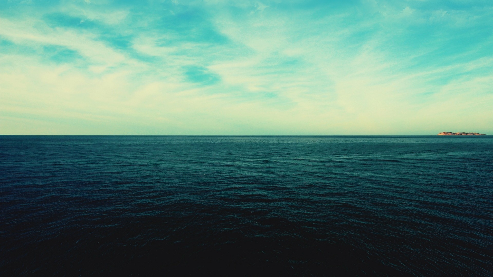 Ocean horizon with clouds and a distant island HD Wallpaper