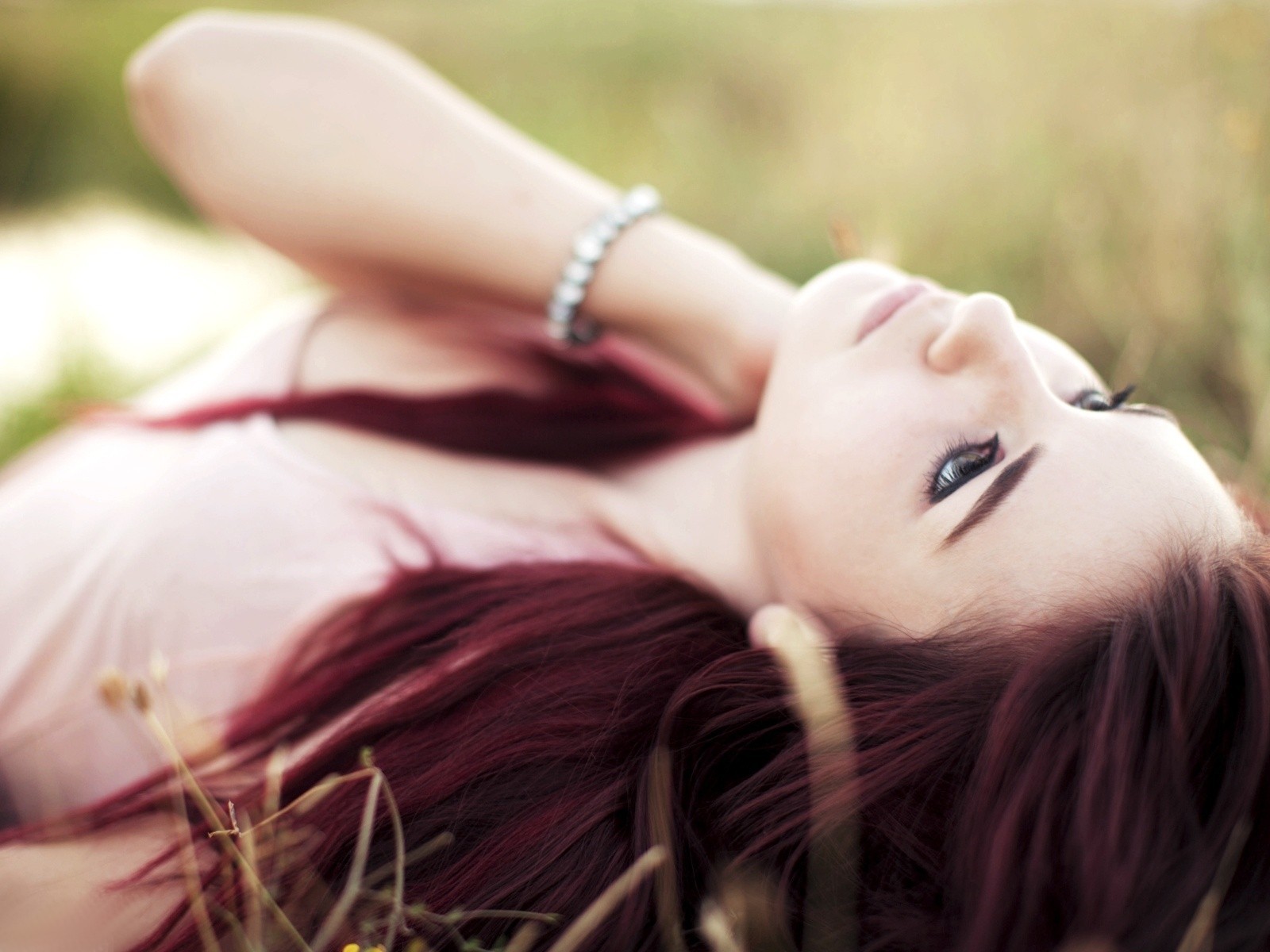 Woman with red hair lying in grass wearing a bracelet HD Wallpaper