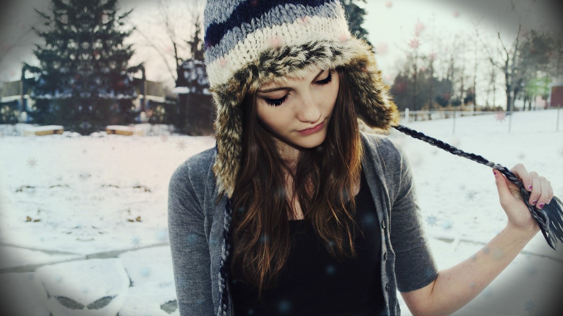 Woman in winter hat holding braided hair in snow HD Wallpaper