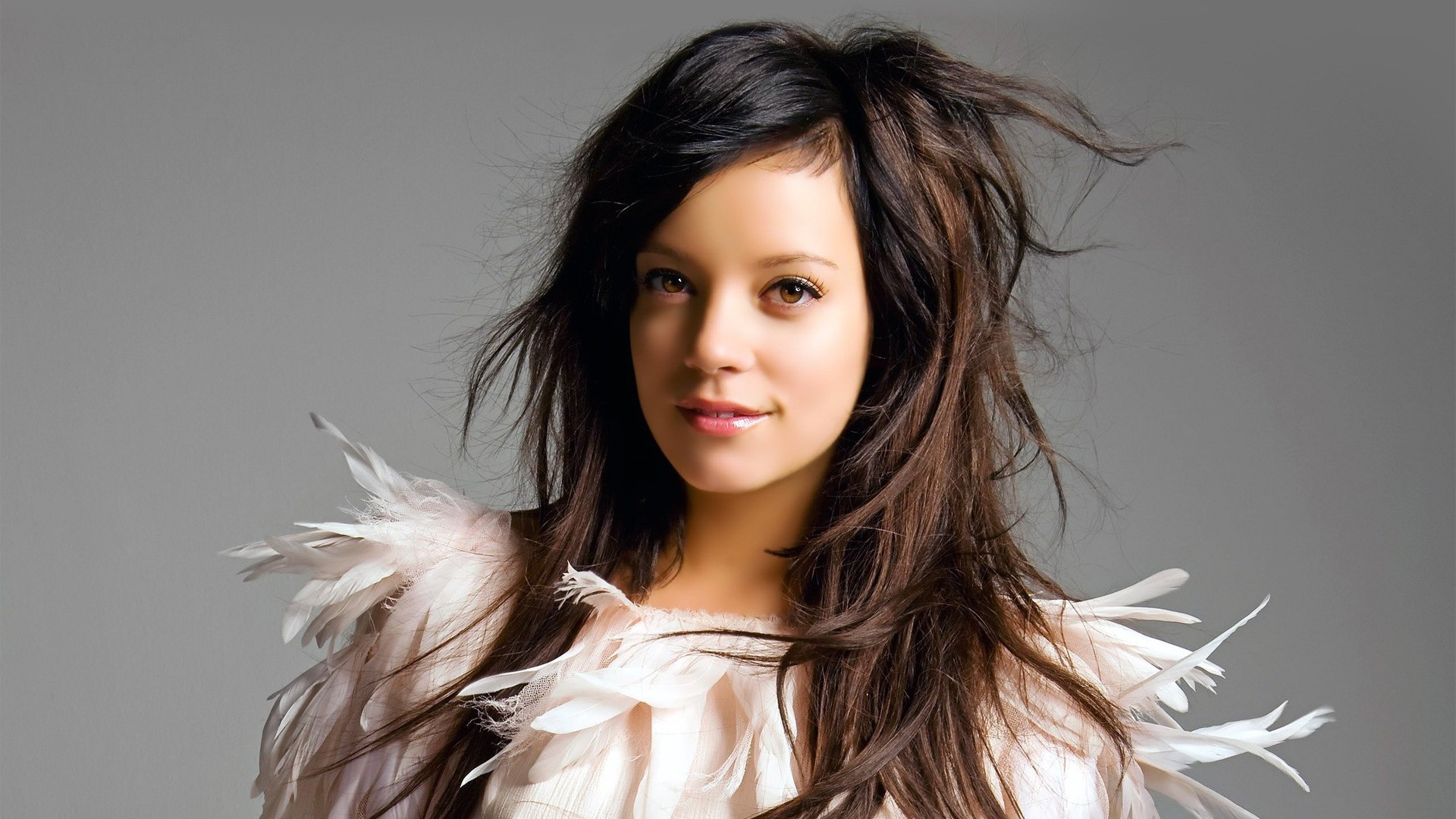 Lily Allen with long brown hair and feathered outfit HD Wallpaper