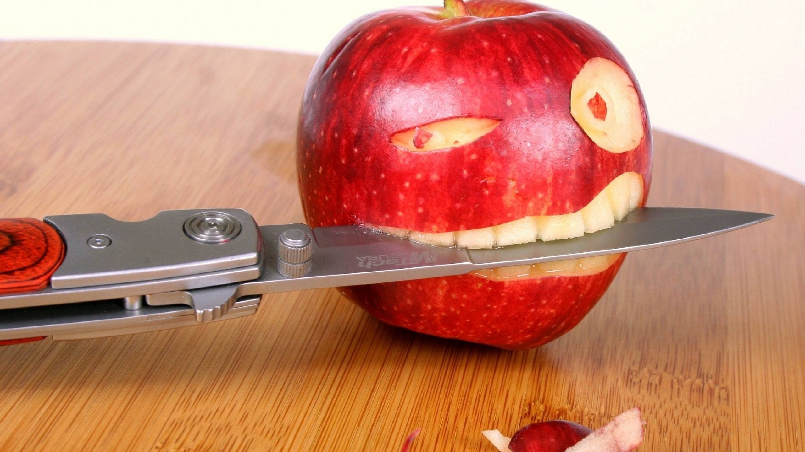 Apple carved into a face with a knife HD Wallpaper