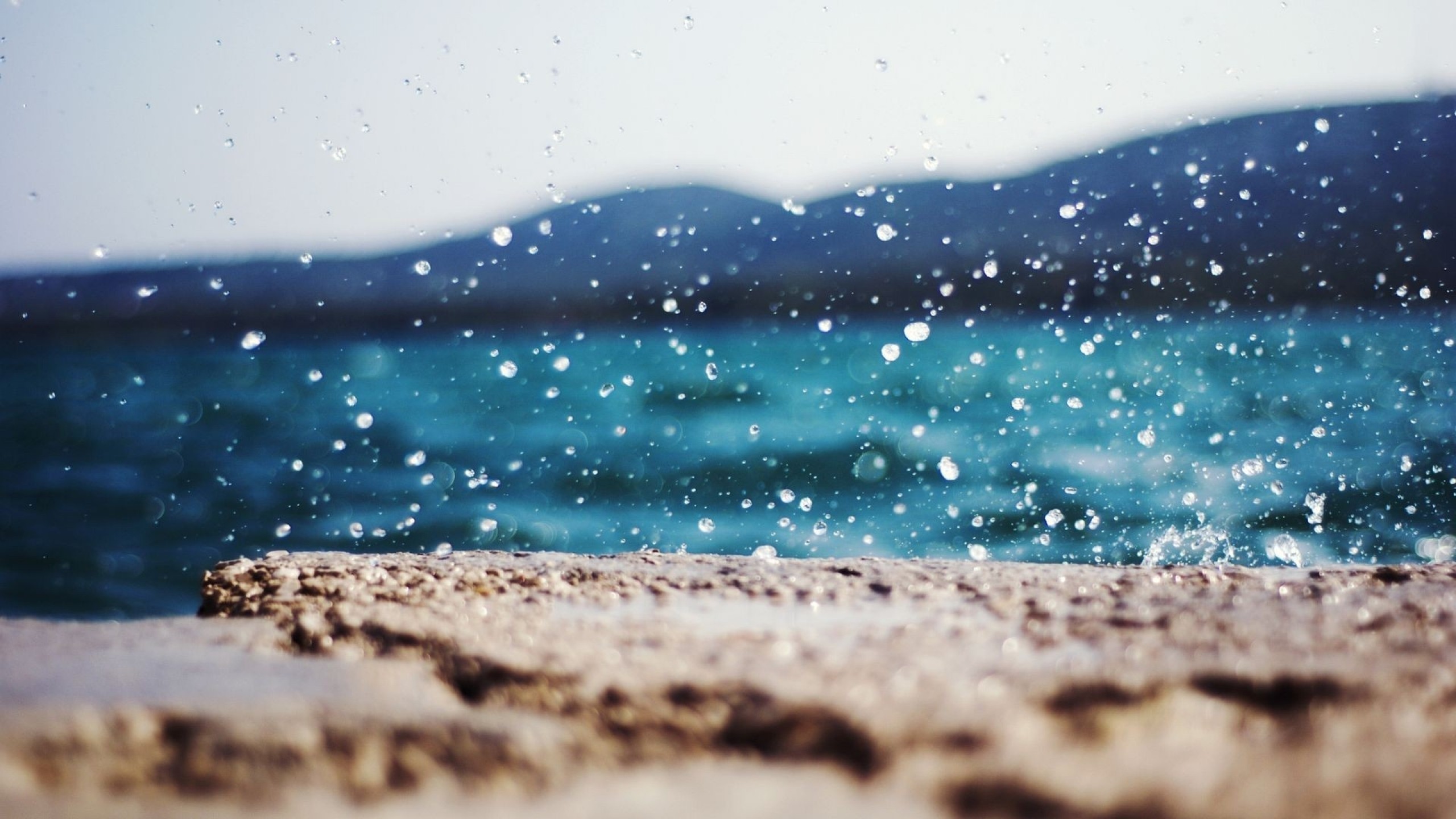 Water drops splashing on a rock by the sea HD Wallpaper