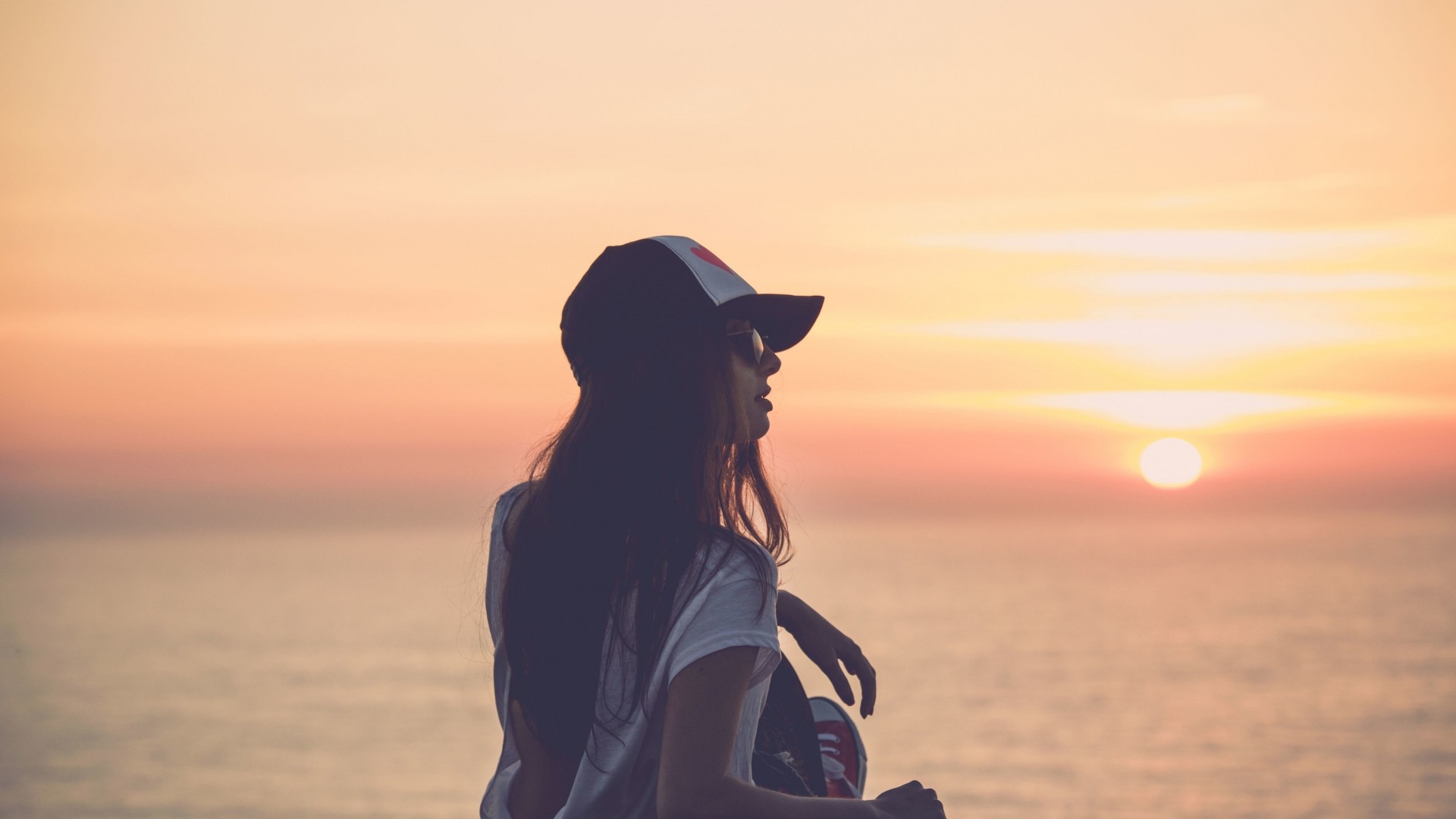 Woman in hat watching sunset over the ocean HD Wallpaper