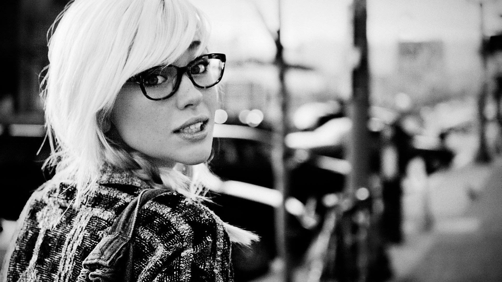 Woman with blonde hair and glasses looking over her shoulder HD Wallpaper