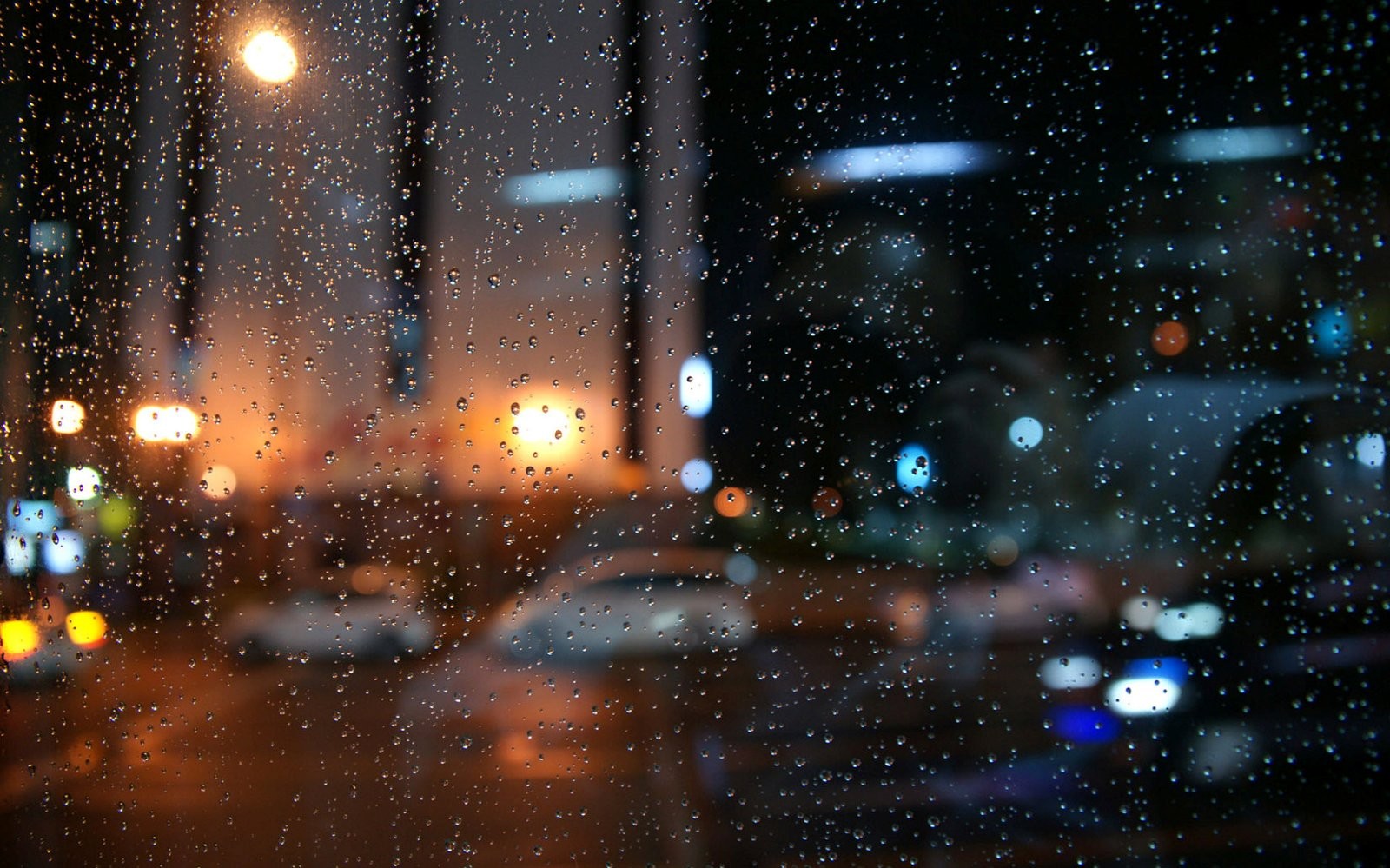Raindrops on glass with bokeh city lights at night HD Wallpaper