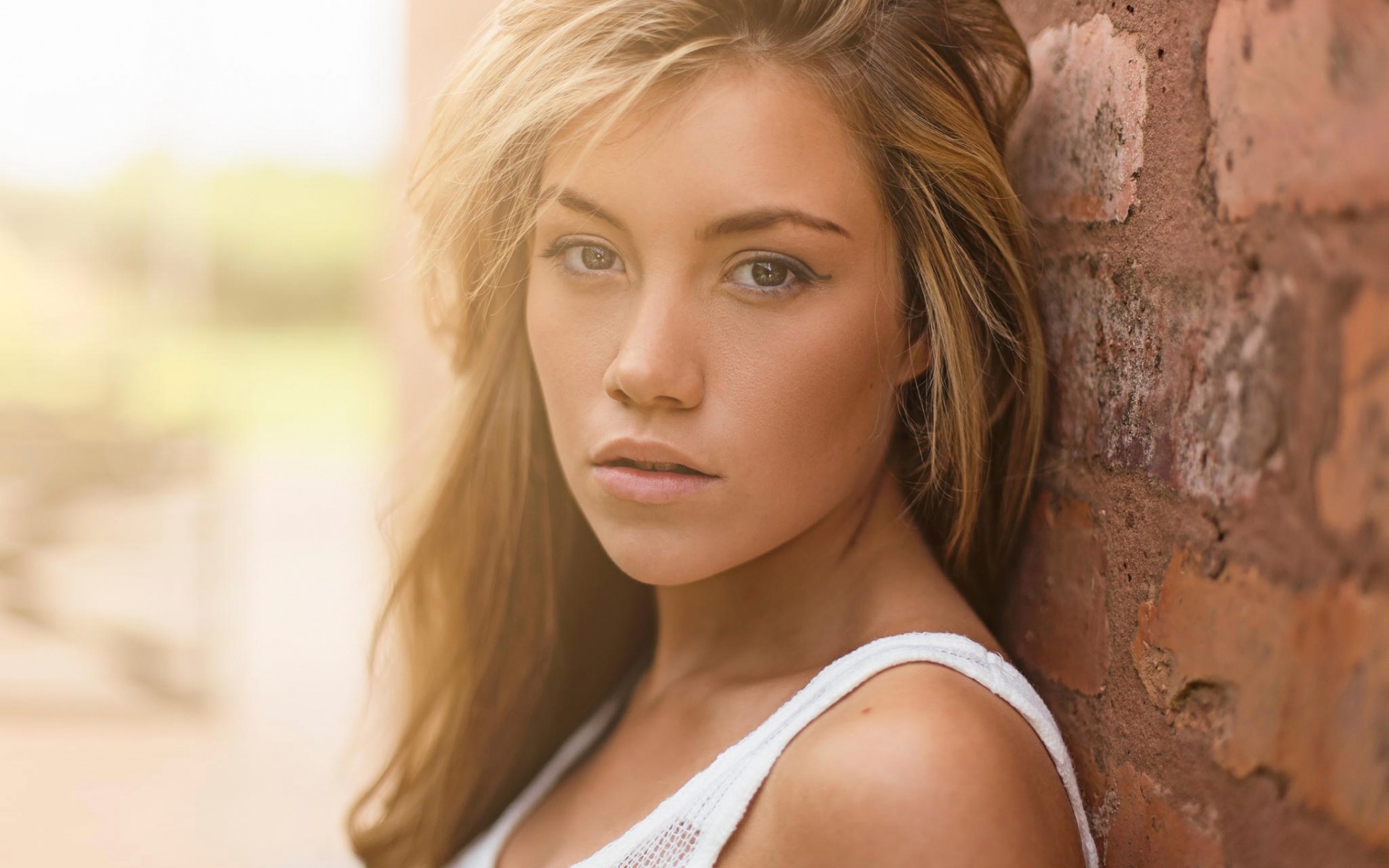 Woman leaning against a brick wall HD Wallpaper