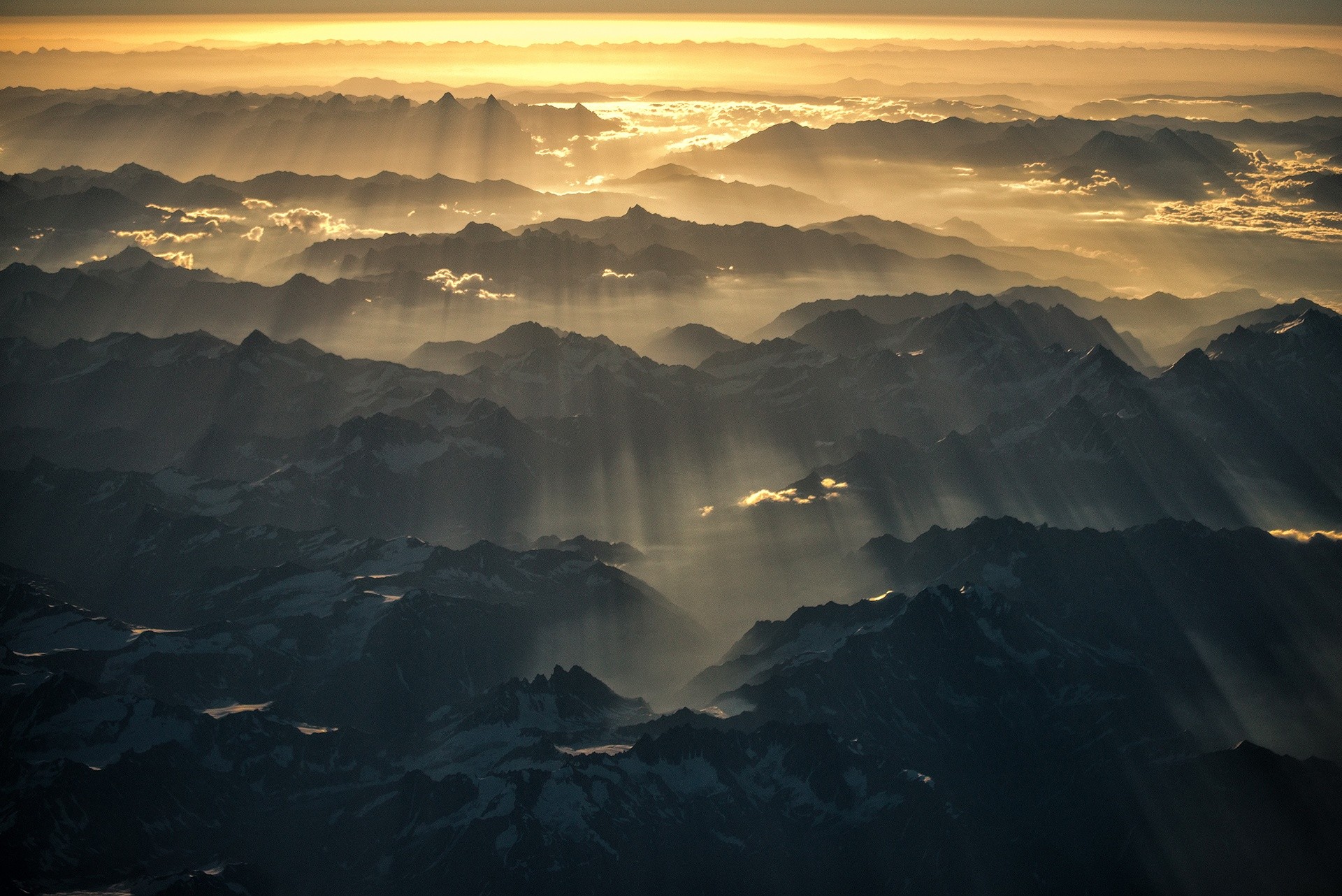 Sunlight beams through mountain ranges at sunset HD Wallpaper