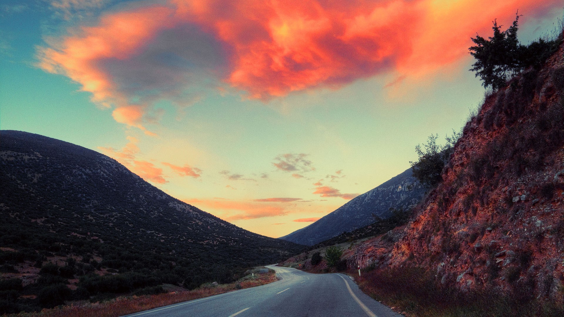A winding road through mountains at sunset HD Wallpaper