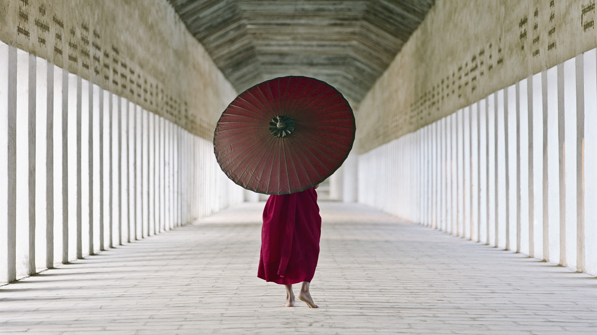 Monk with umbrella in a long corridor HD Wallpaper