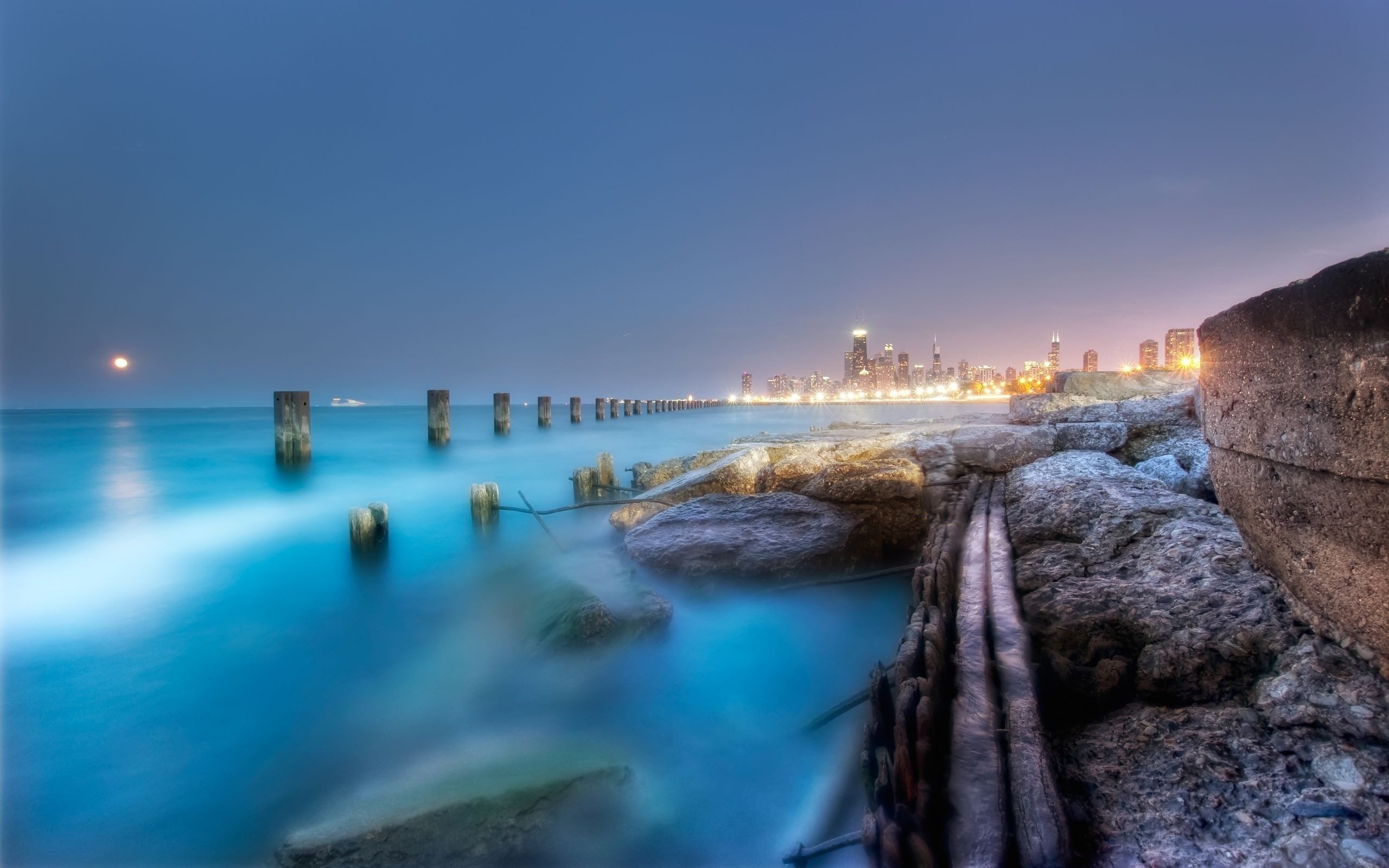 Chicago skyline at night over Lake Michigan with rocky shore HD Wallpaper