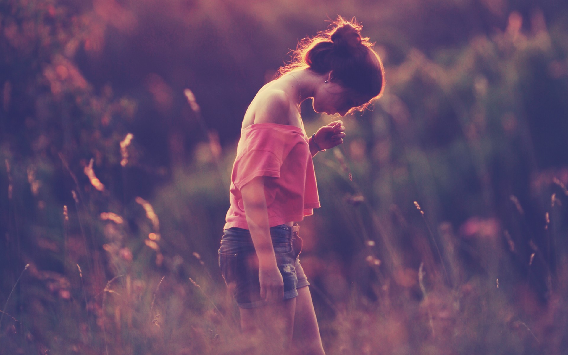 Woman in pink shirt and denim shorts in a field at sunset HD Wallpaper