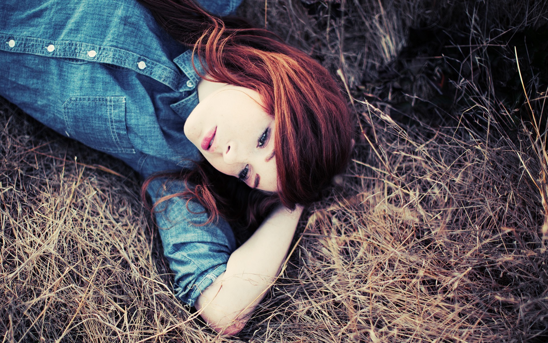 Redhead woman lying in dry grass outdoors HD Wallpaper