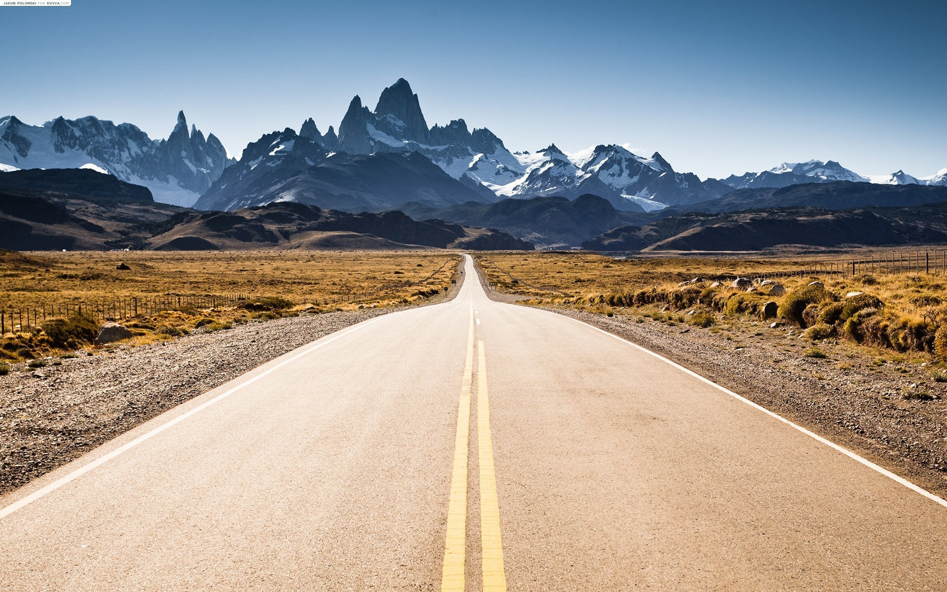 Road leading to snow-capped mountains under a clear sky HD Wallpaper