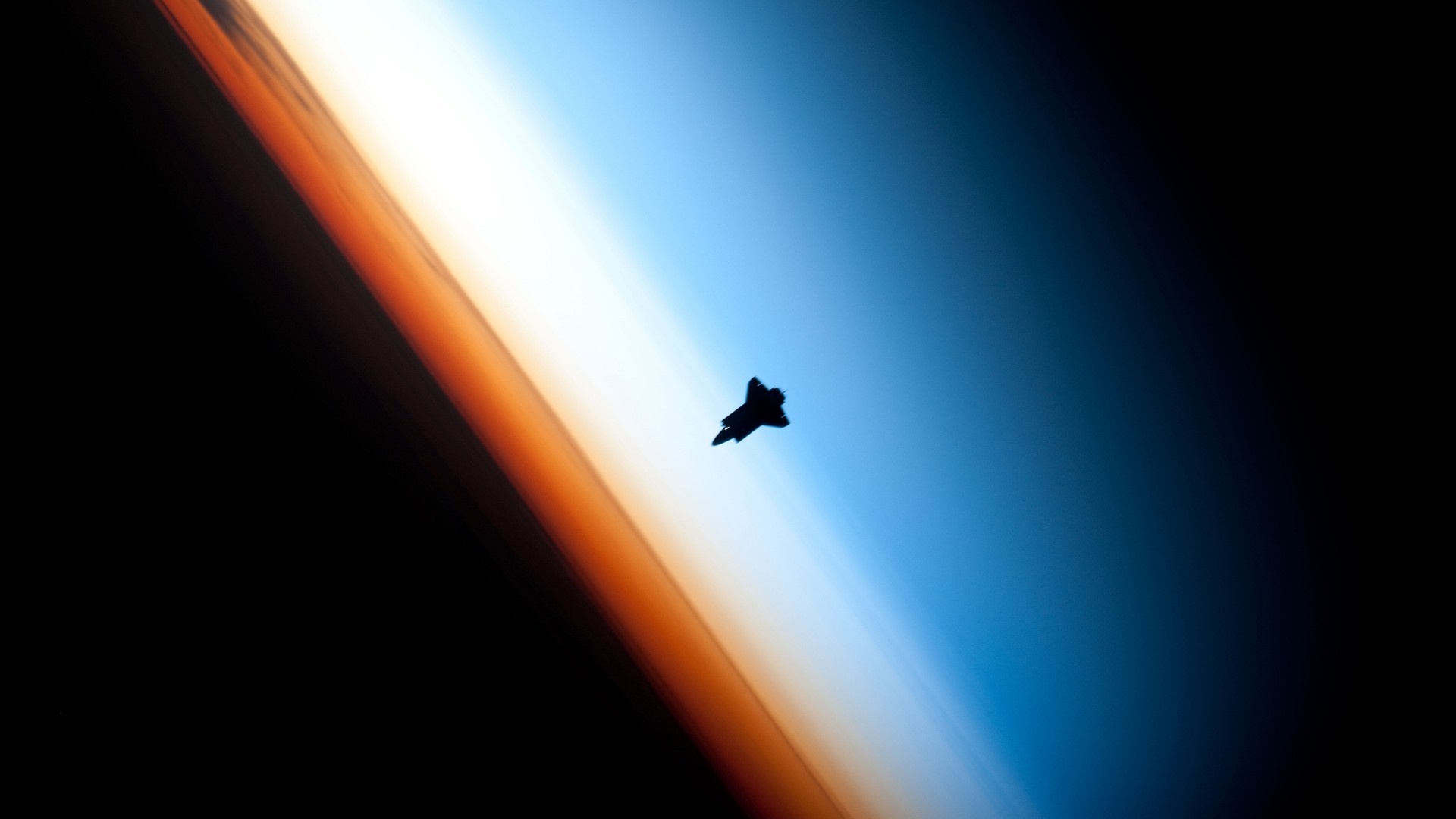 Space Shuttle silhouetted against Earth's atmosphere HD Wallpaper