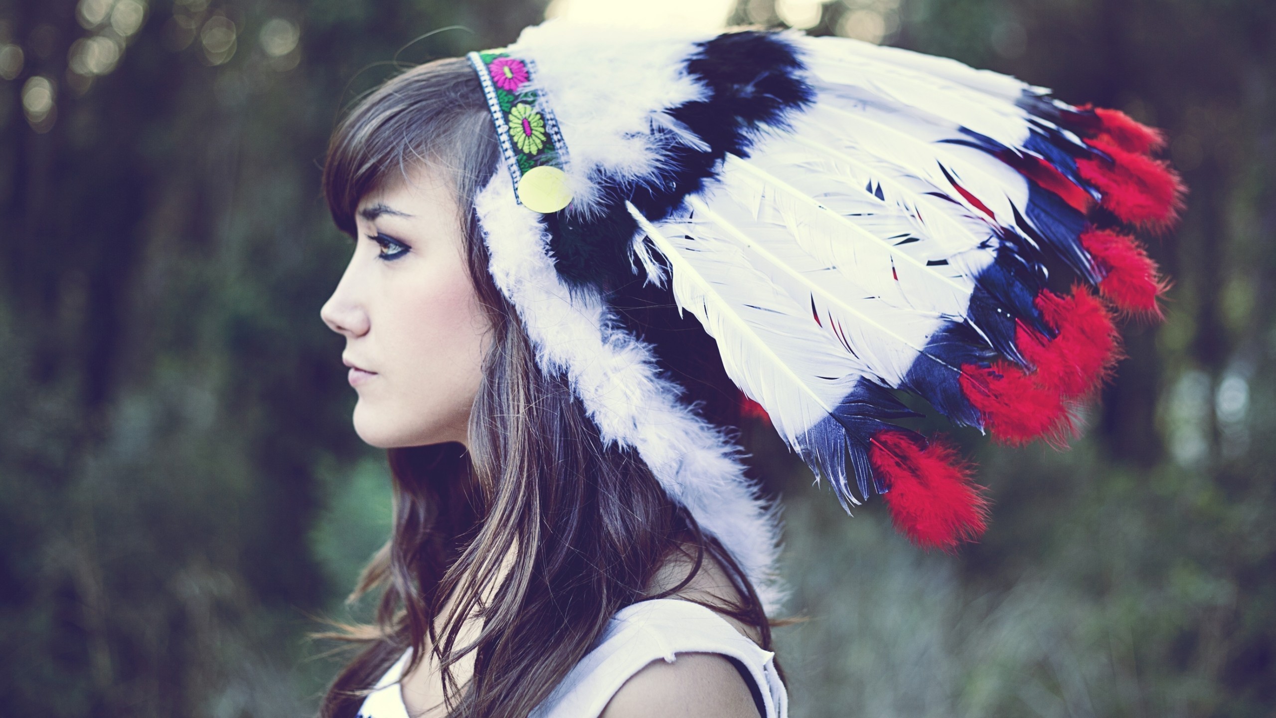 Woman wearing a colorful feathered headdress outdoors HD Wallpaper