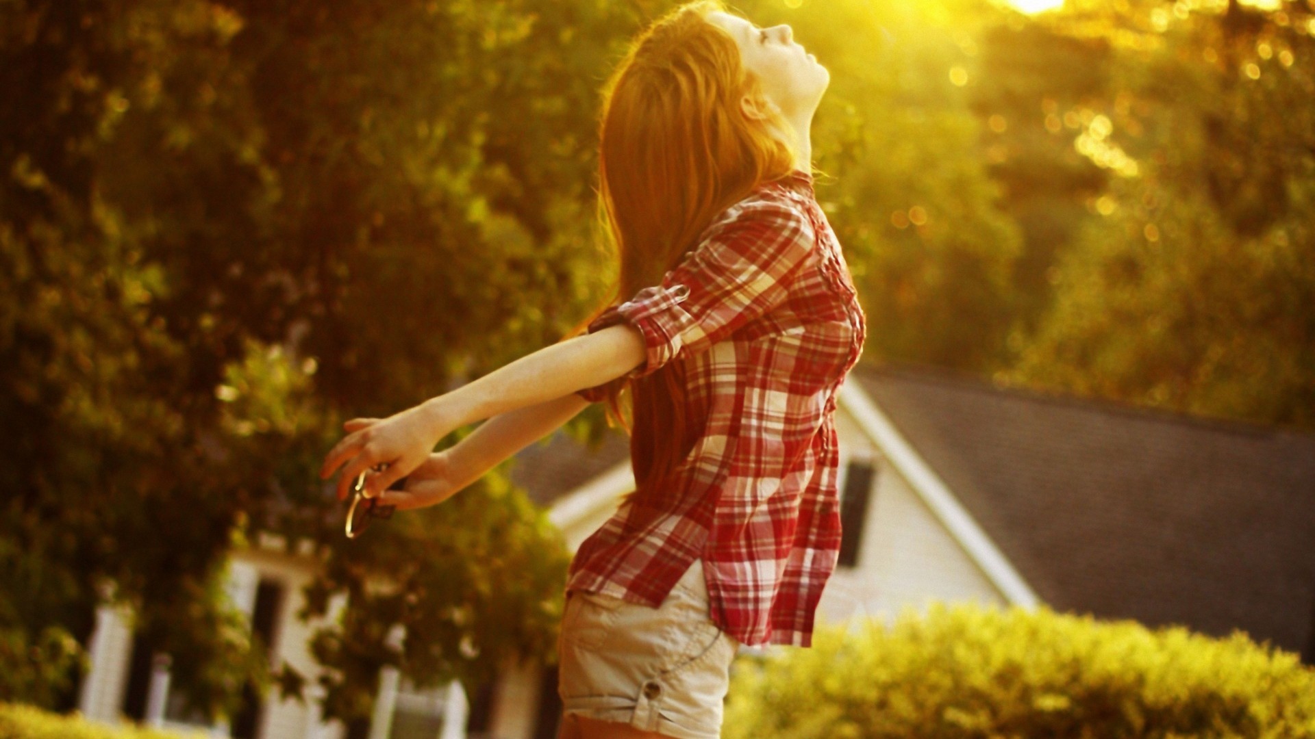 Woman in plaid shirt with arms outstretched in sunlight HD Wallpaper