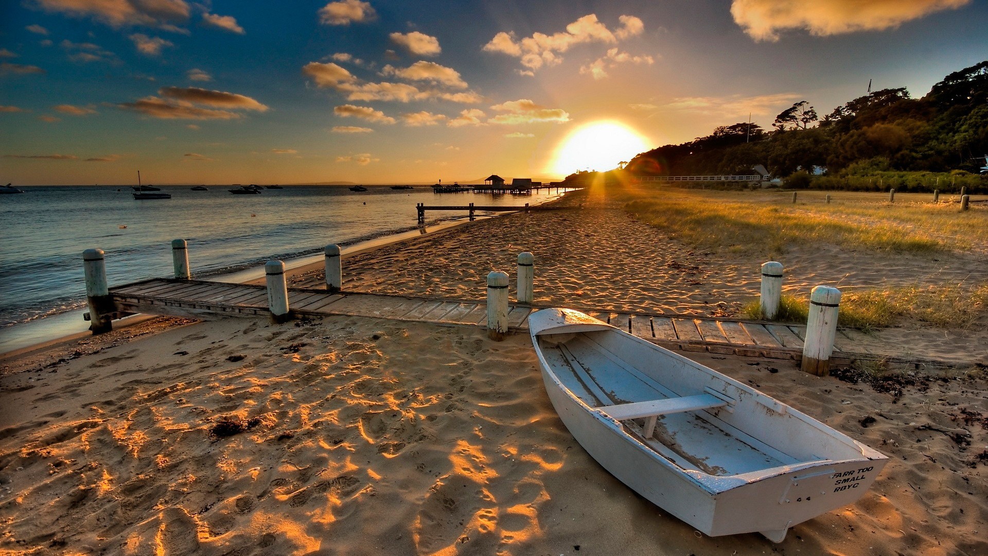 Sunset over a beach with a boat and pier HD Wallpaper