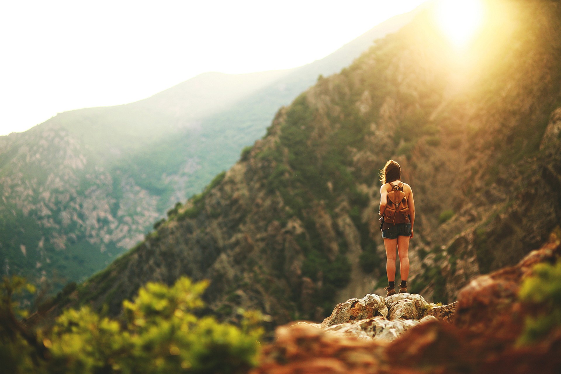 Woman with backpack on mountain overlooking valley at sunset HD Wallpaper