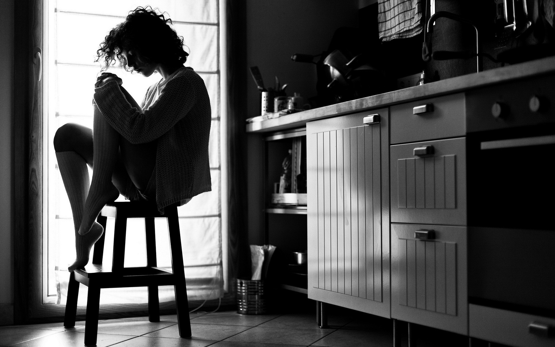 Monochrome silhouette of a woman with curly hair sitting in a kitchen HD Wallpaper