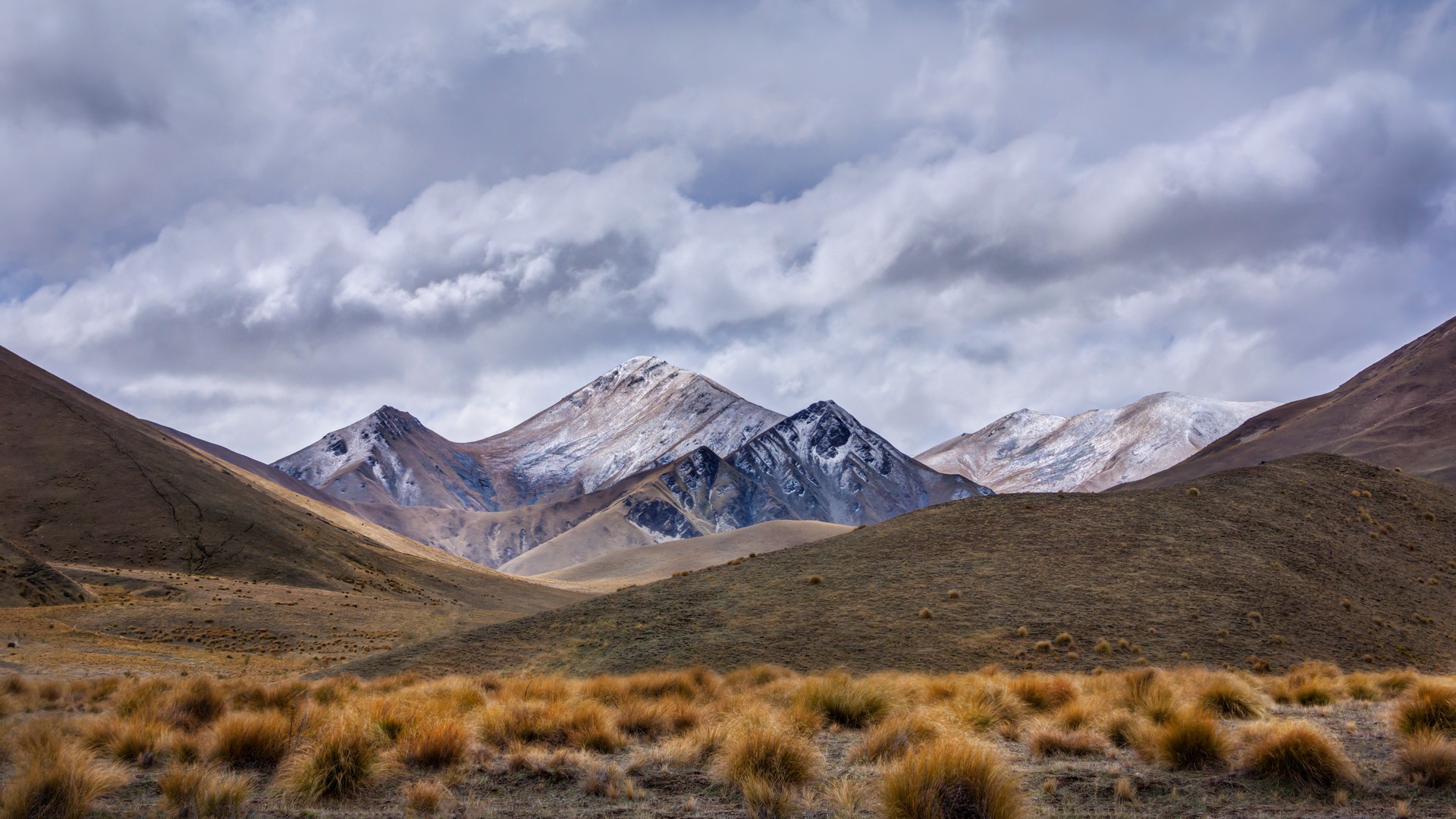 Snow-capped mountains under a cloudy sky HD Wallpaper