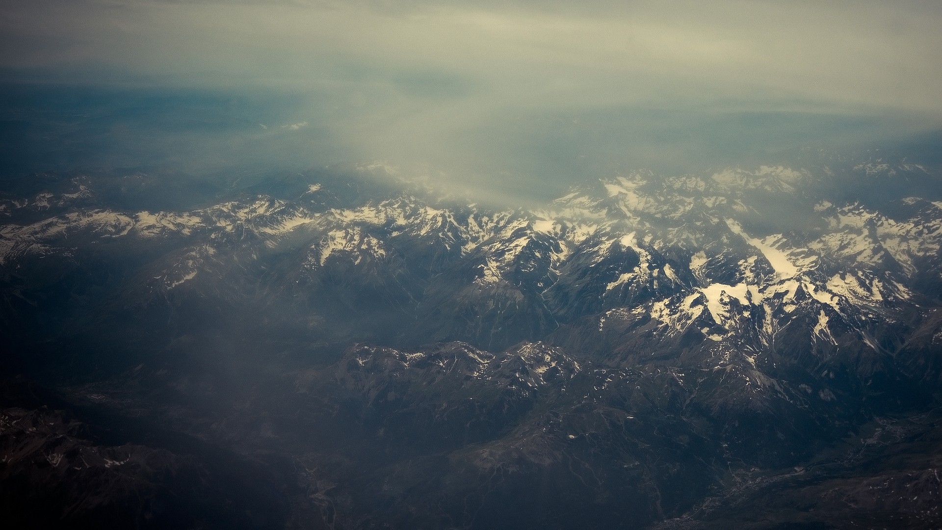 Aerial view of snow-capped mountains shrouded in mist HD Wallpaper
