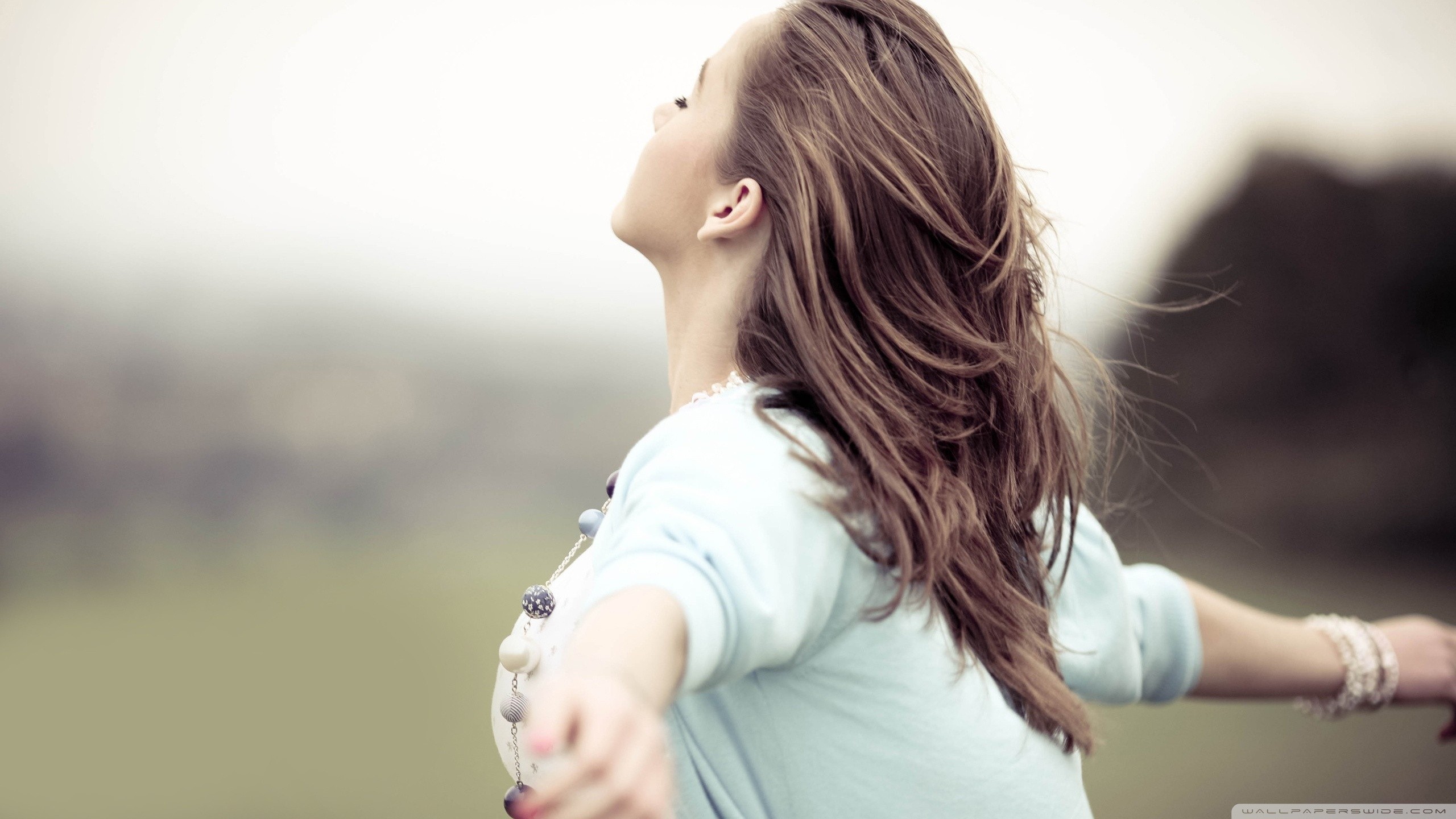 Woman with arms outstretched in a field HD Wallpaper