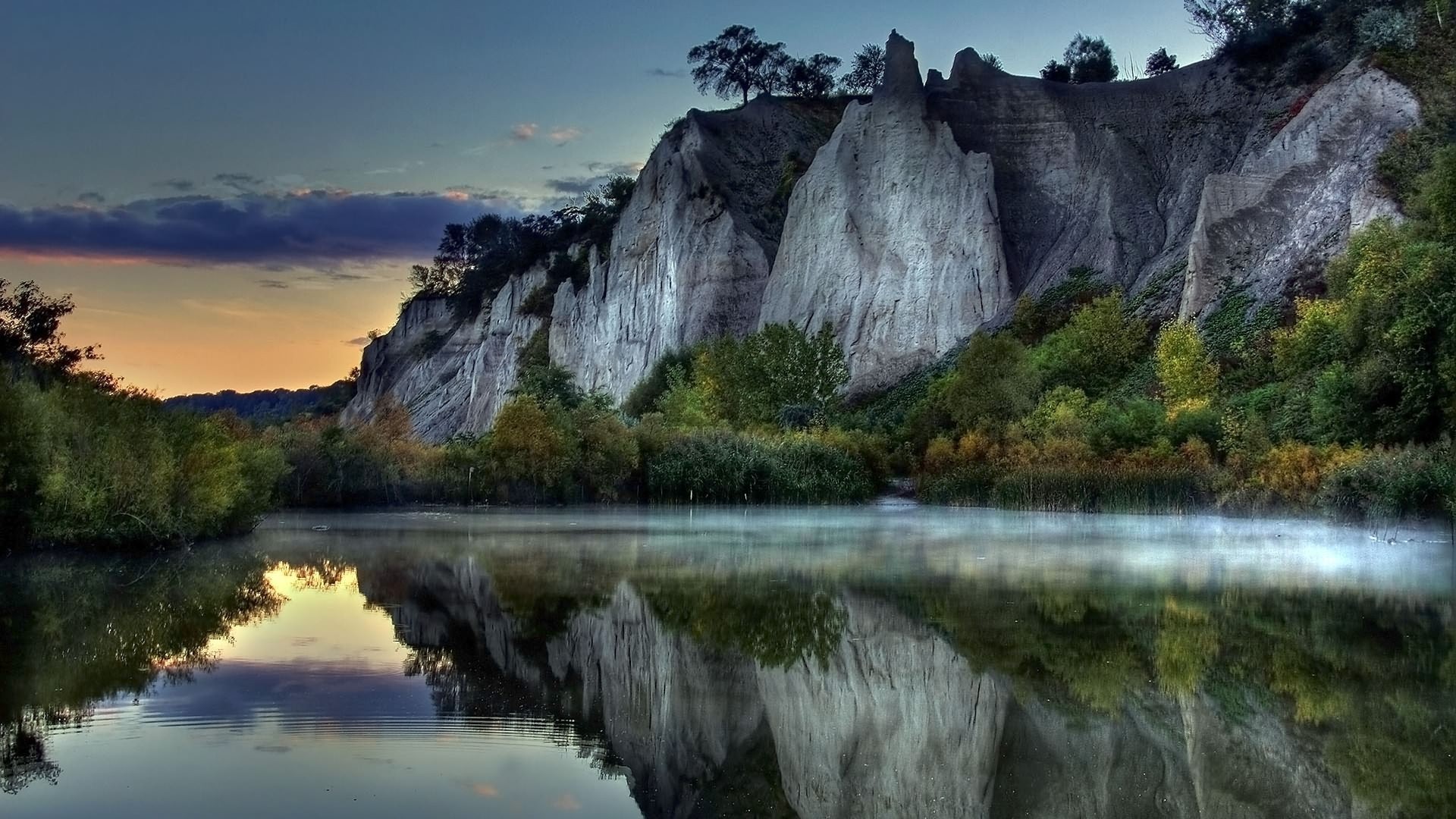 Rock formations reflected in a misty lake at sunset HD Wallpaper
