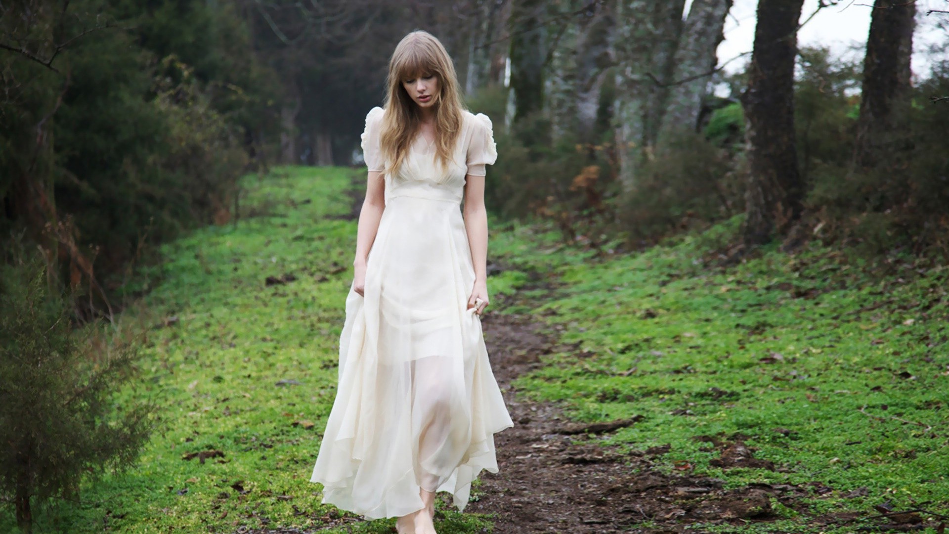 Taylor Swift in a white dress walking in a forest HD Wallpaper