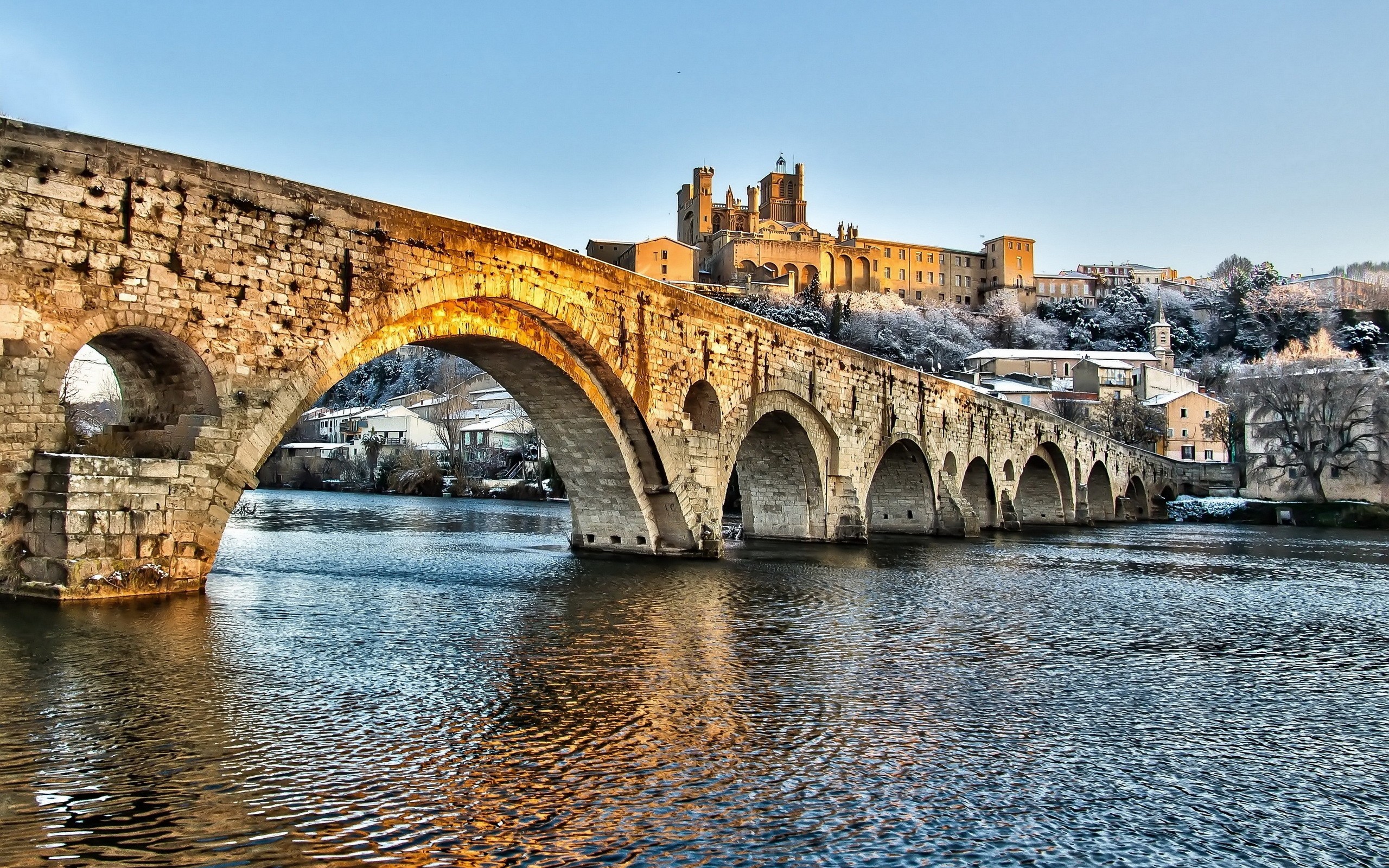 Stone bridge over a river with a castle on a snowy hill HD Wallpaper