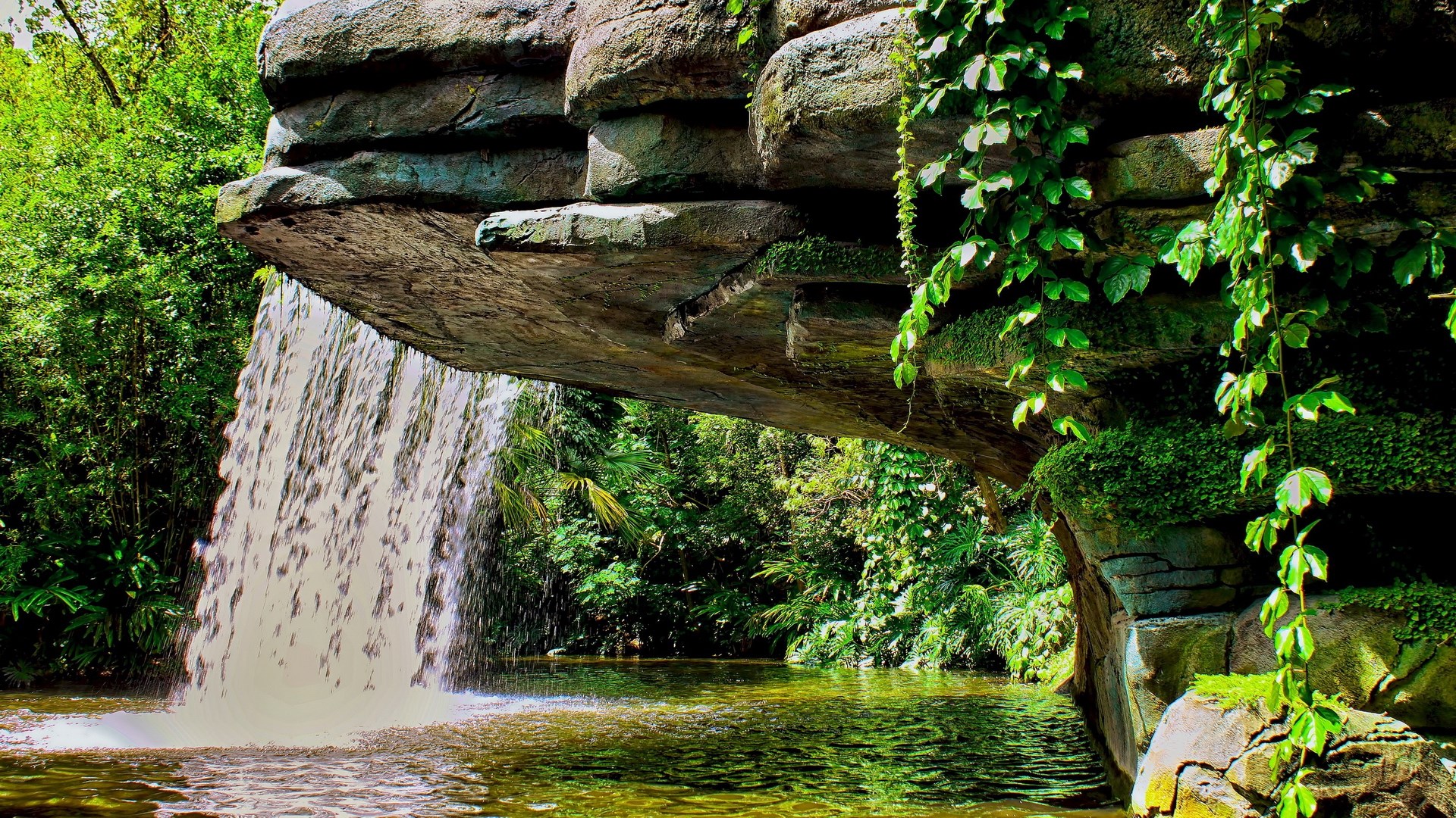 Waterfall cascading from rock formation into a pool HD Wallpaper
