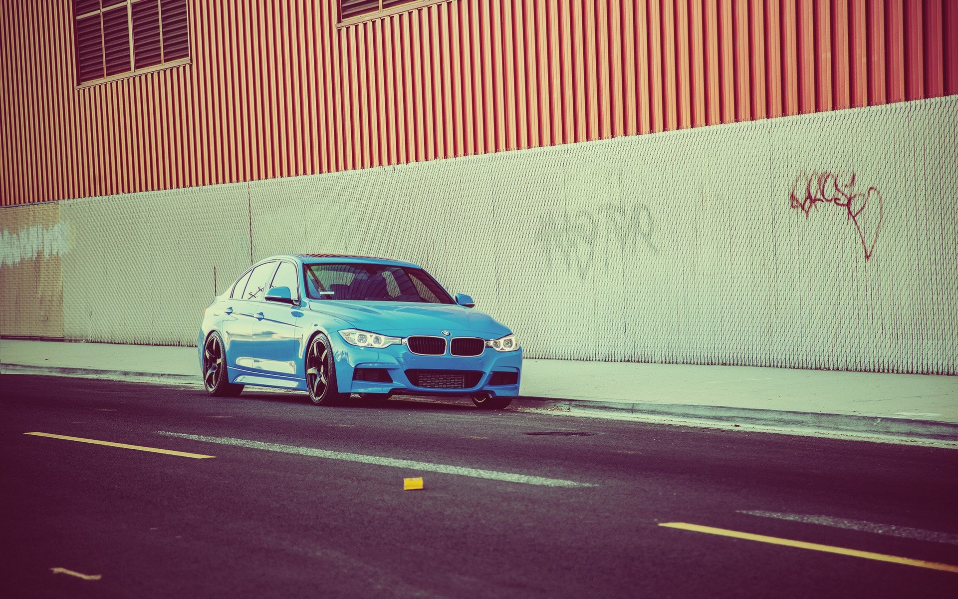 Blue BMW sedan parked by a graffiti-covered wall HD Wallpaper