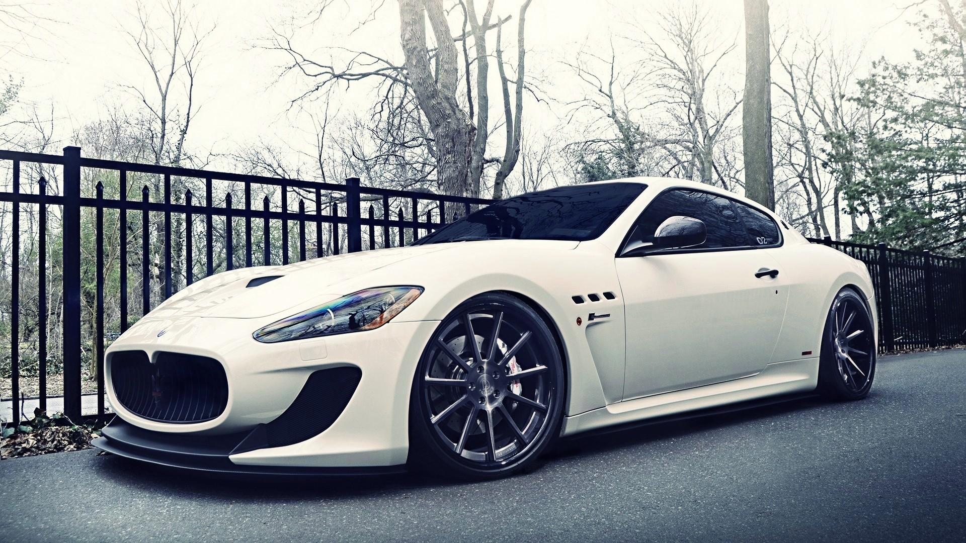 White Maserati GranTurismo parked by a black fence HD Wallpaper