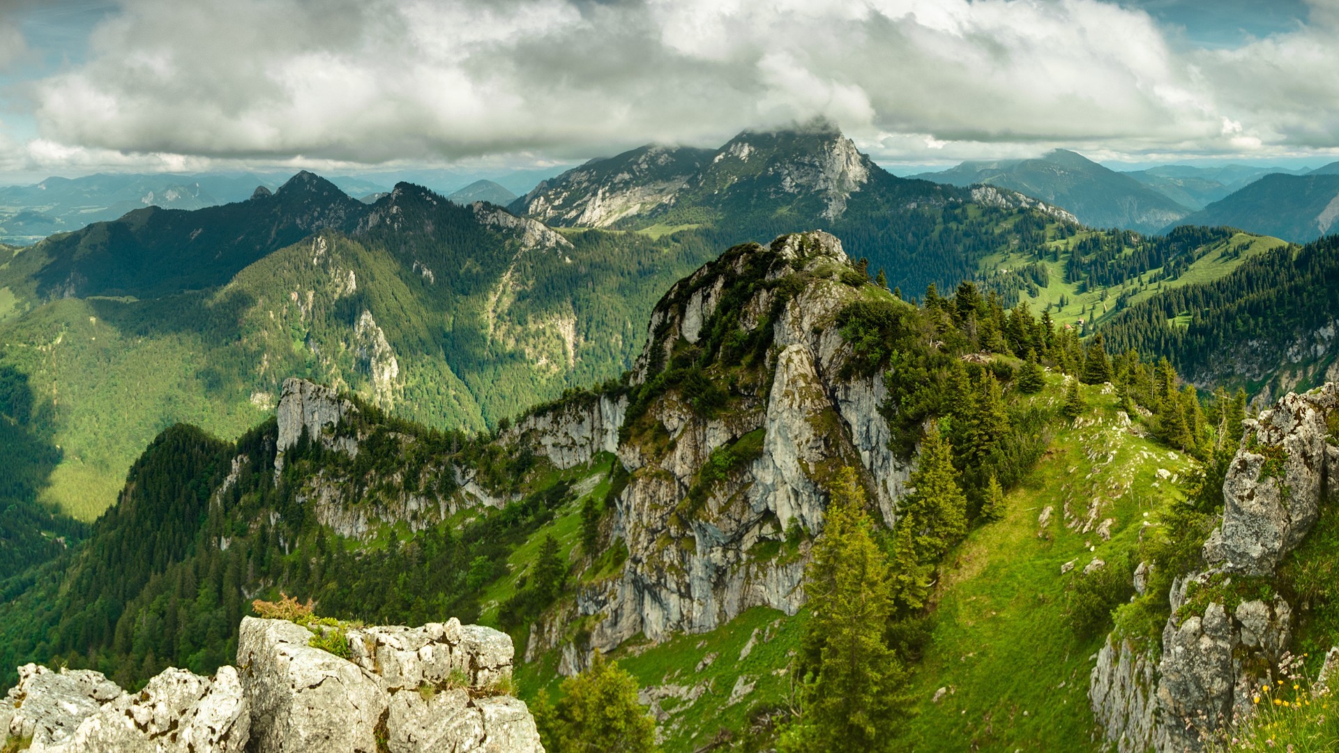Green mountains and rocky peaks under cloudy sky HD Wallpaper