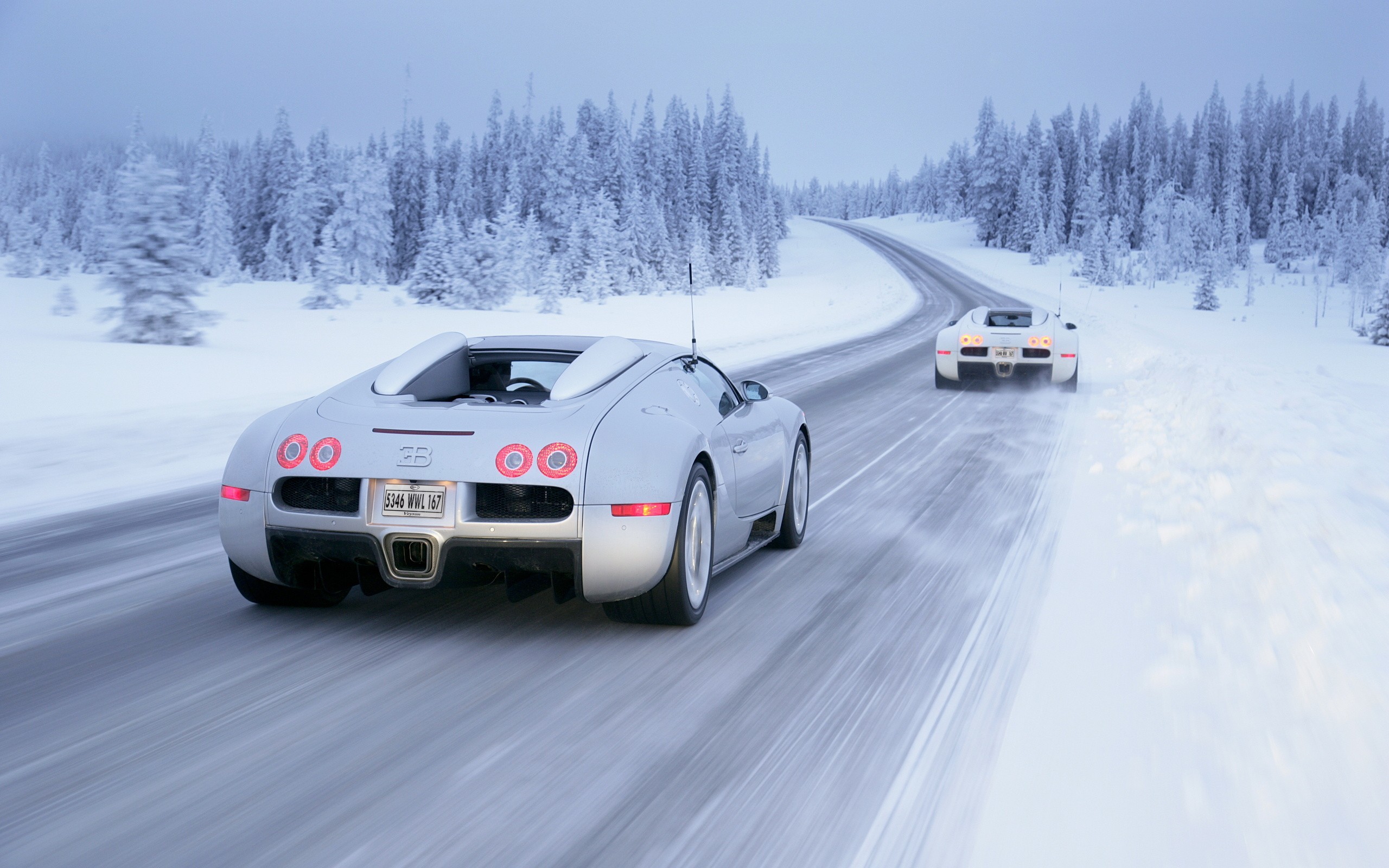 Two Bugatti Veyrons driving on a snowy road HD Wallpaper