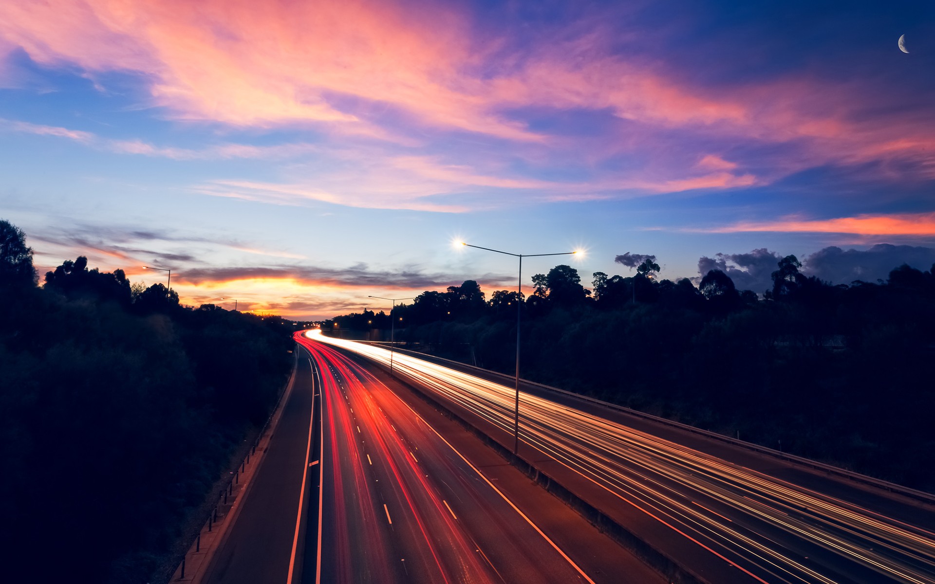 Highway light trails at sunset with a crescent moon HD Wallpaper